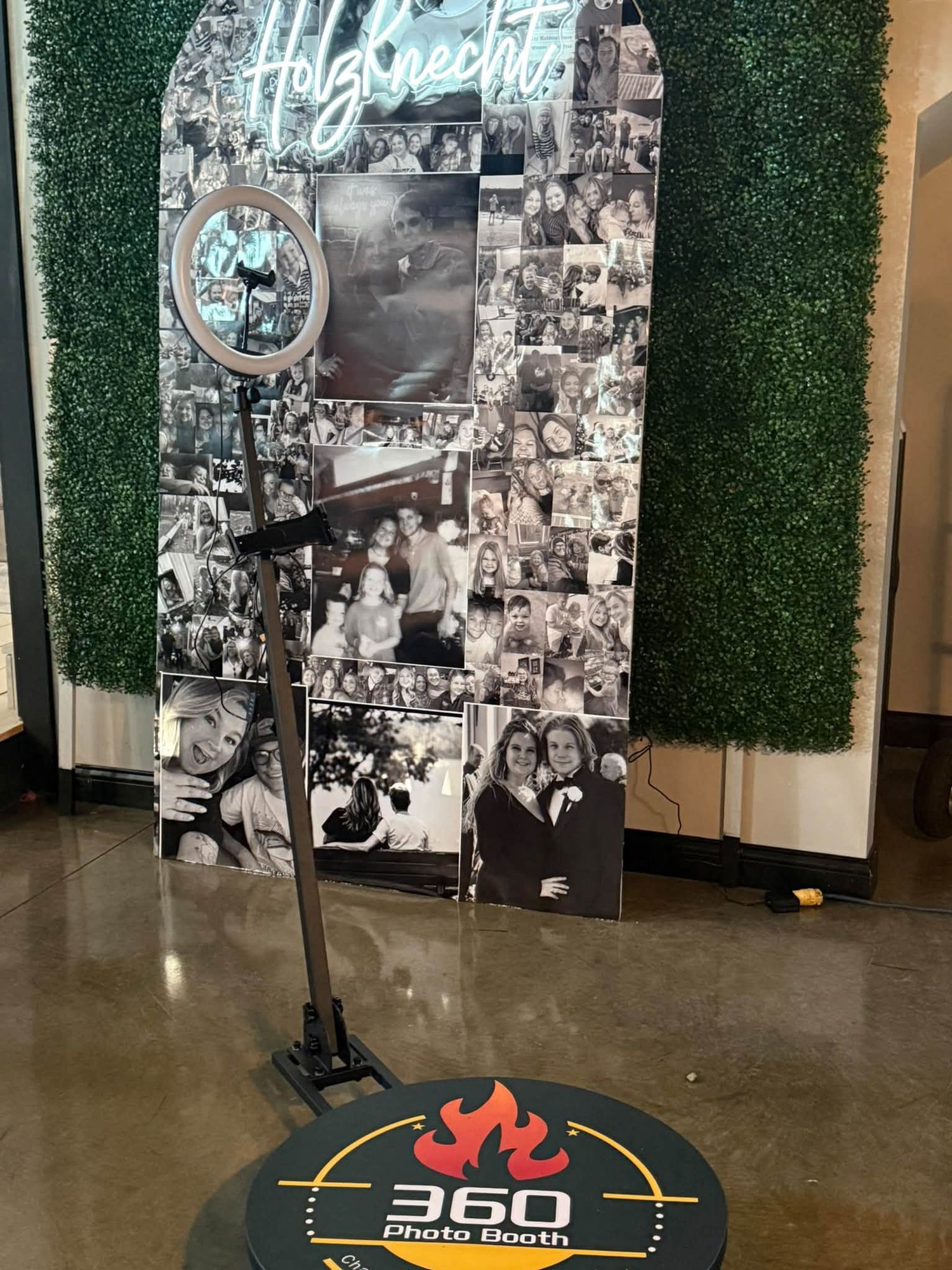 360 photo booth setup with greenery wall and custom photo backdrop for an event.