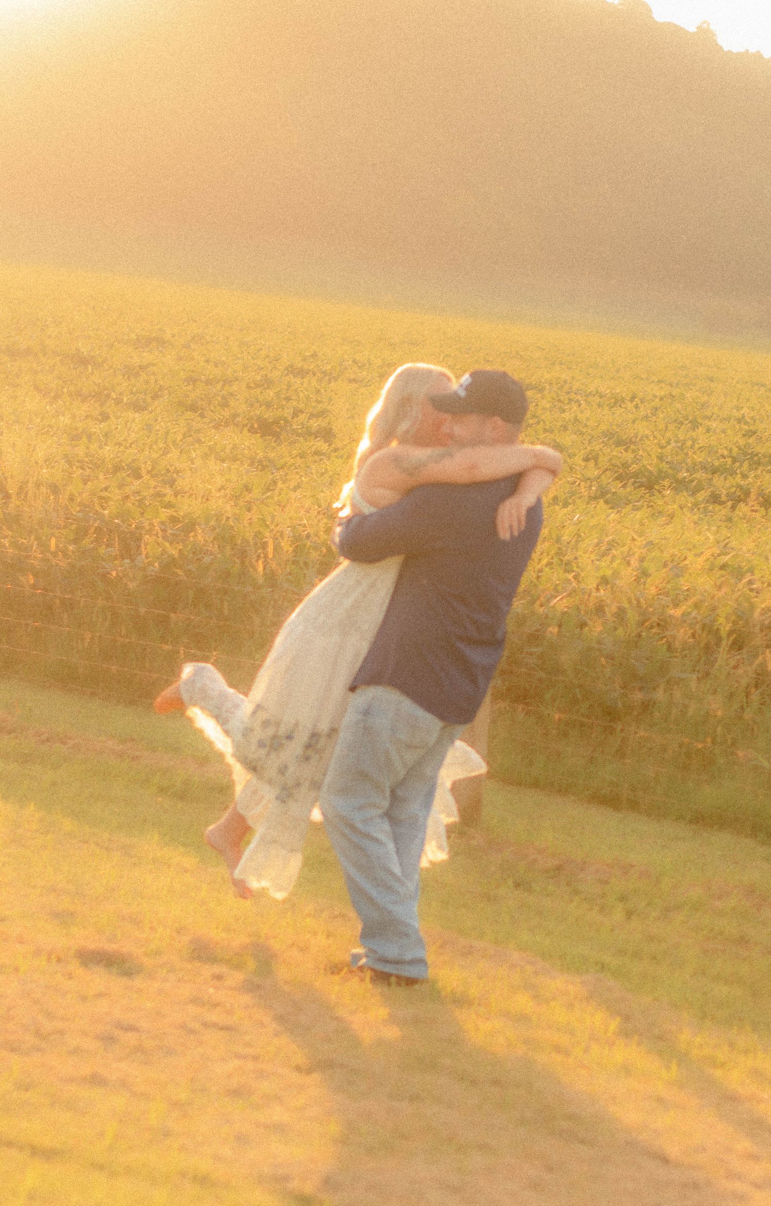Couple embracing in a field during warm golden-hour light.