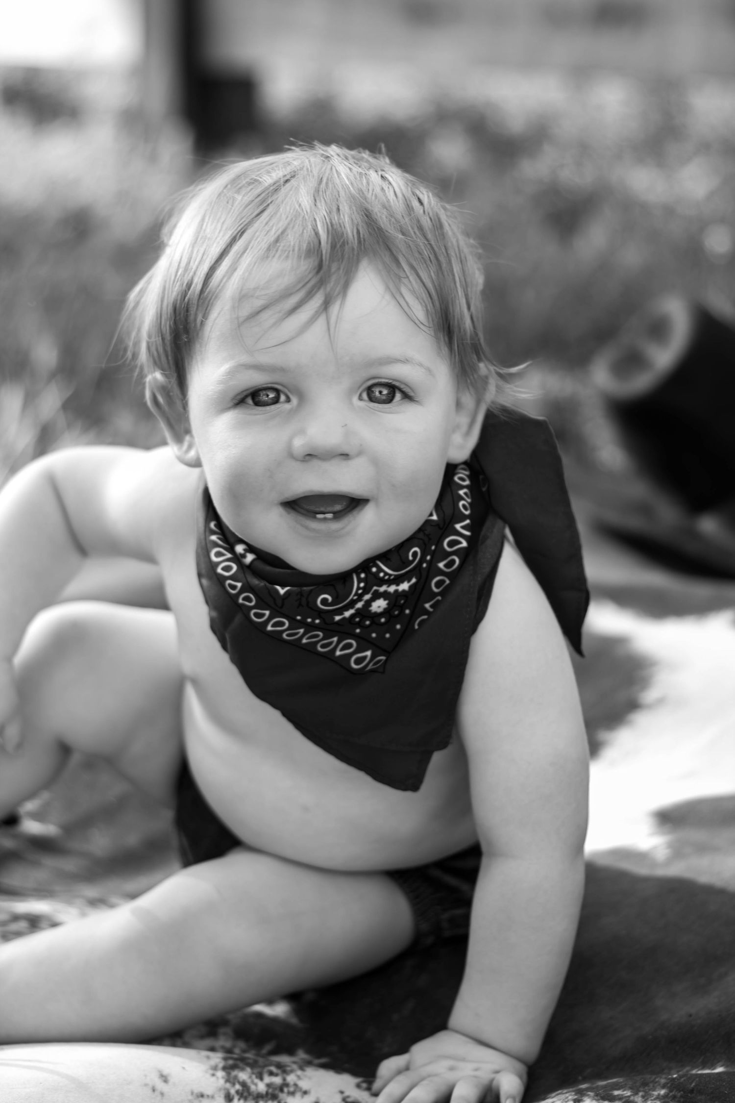 Black-and-white portrait of a smiling baby during an outdoor milestone session.