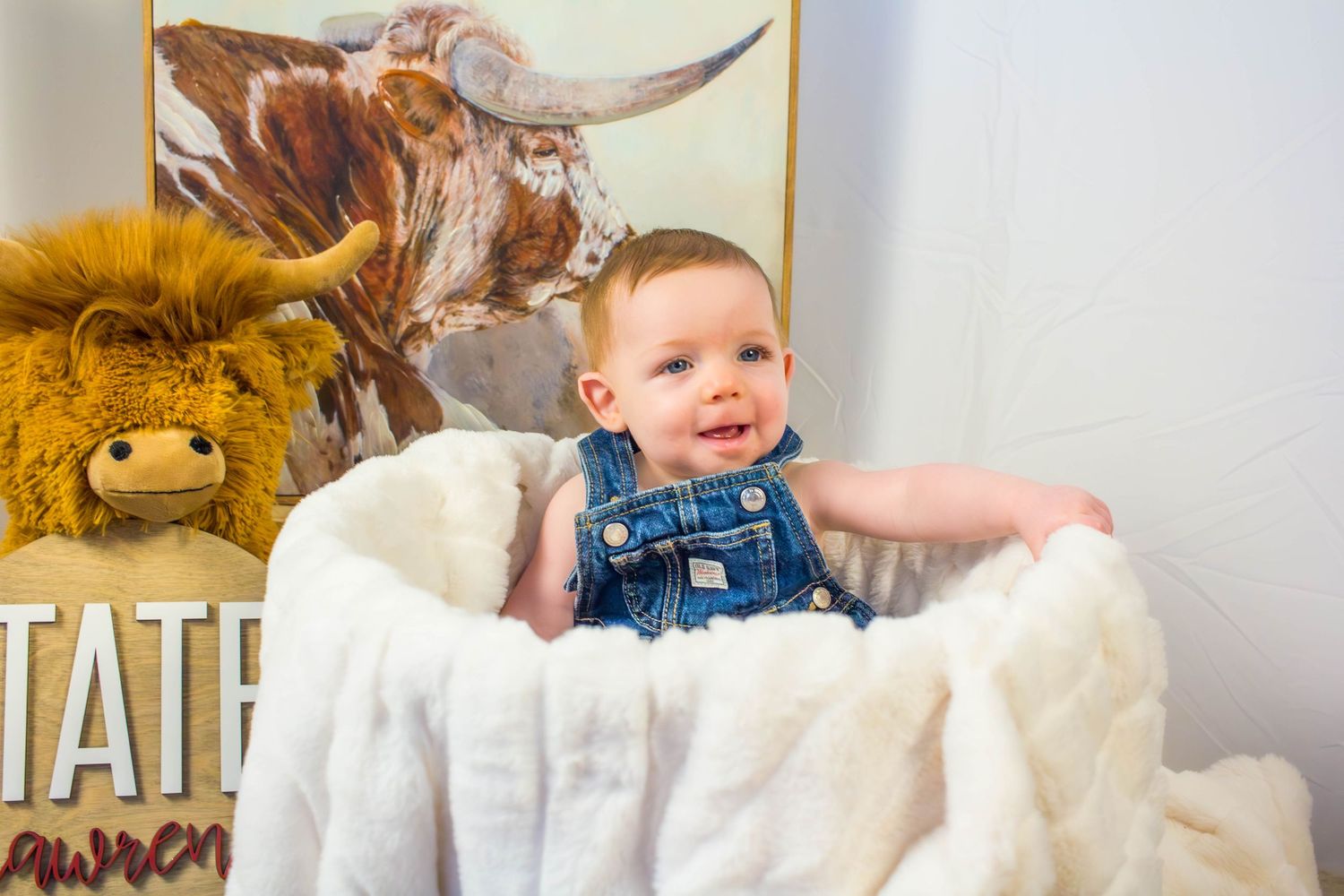 Baby sitting beside western-themed decorations during a milestone session.
