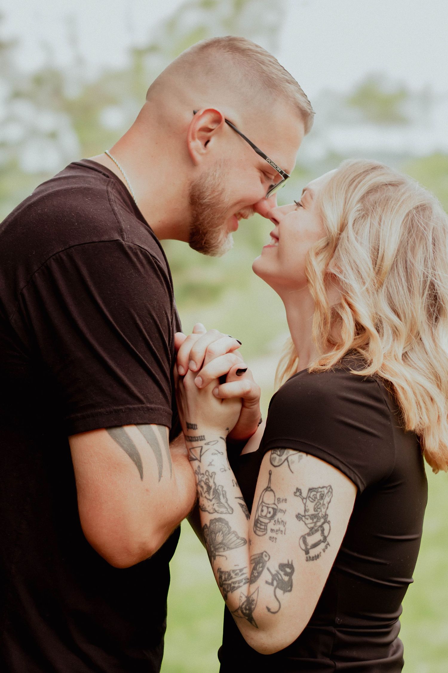 Couple holding hands and smiling at each other during their engagement session.