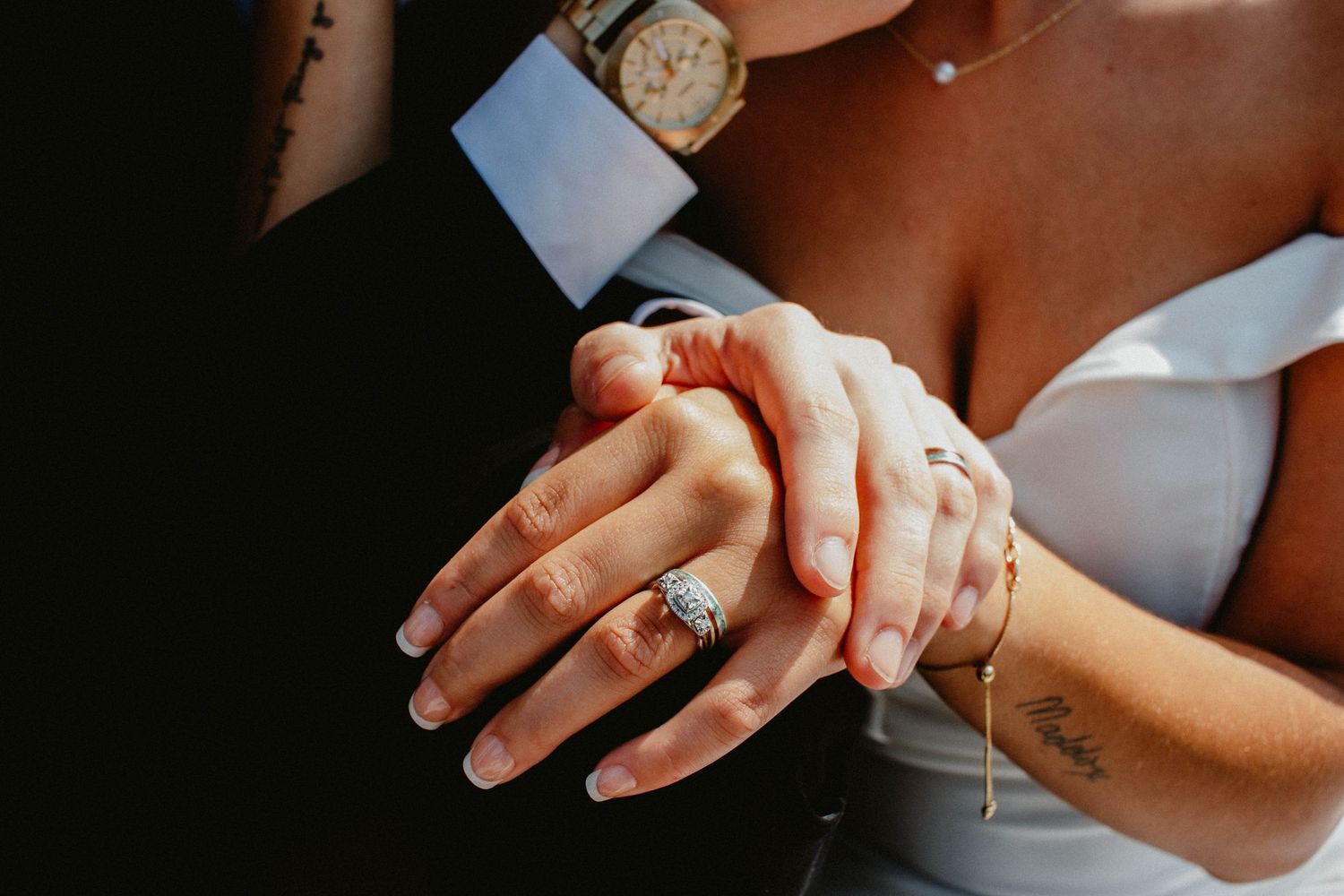 Close-up of a newlywed couple holding hands and showing their wedding rings.