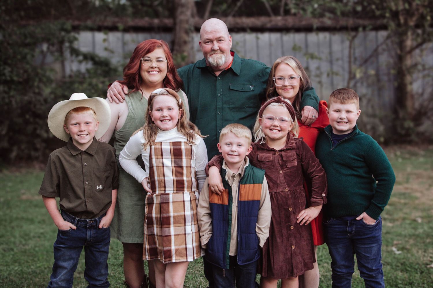 Large family posing together in a field in coordinating fall outfits