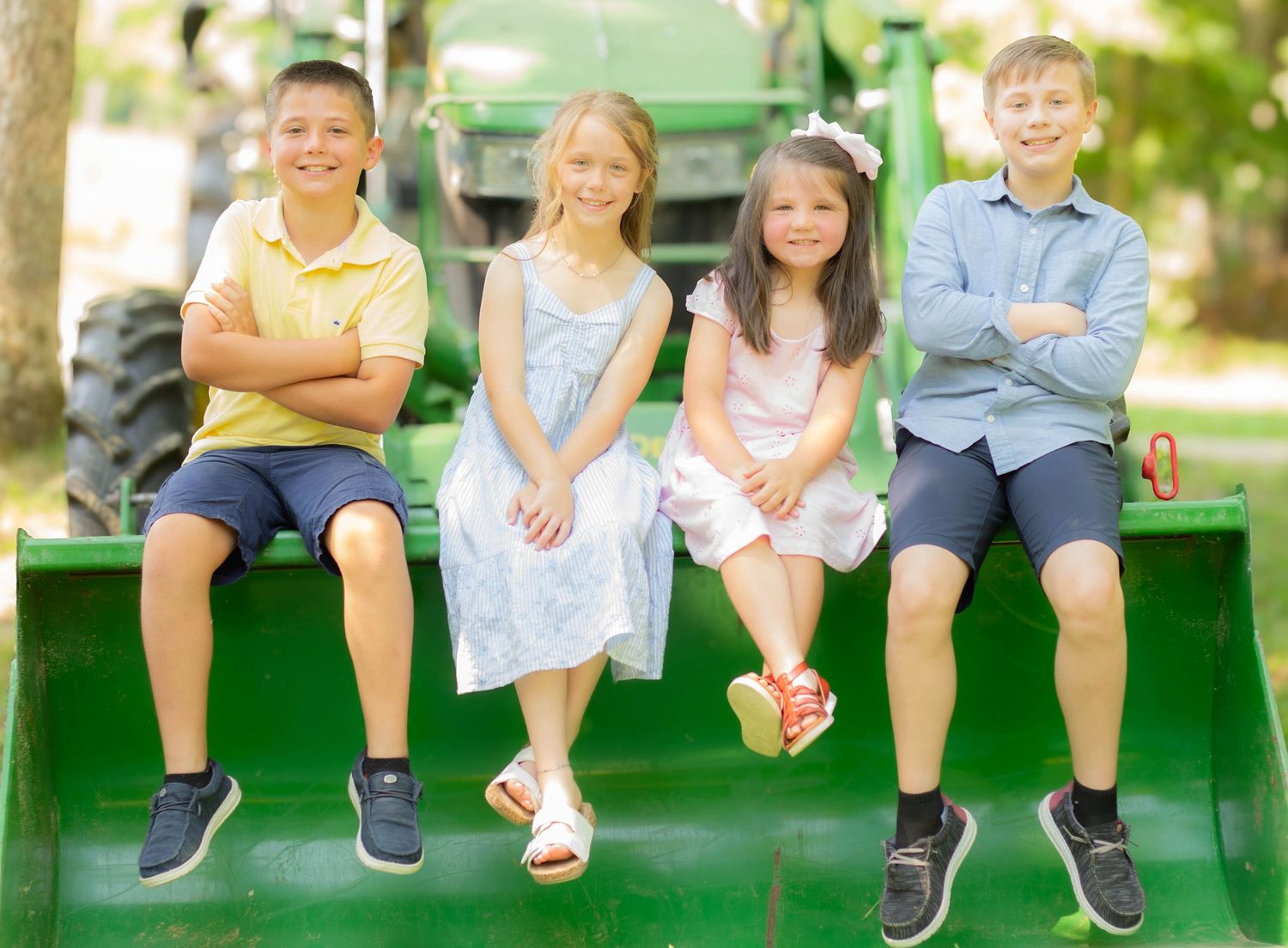 Four children sitting together outdoors during a family photography session.