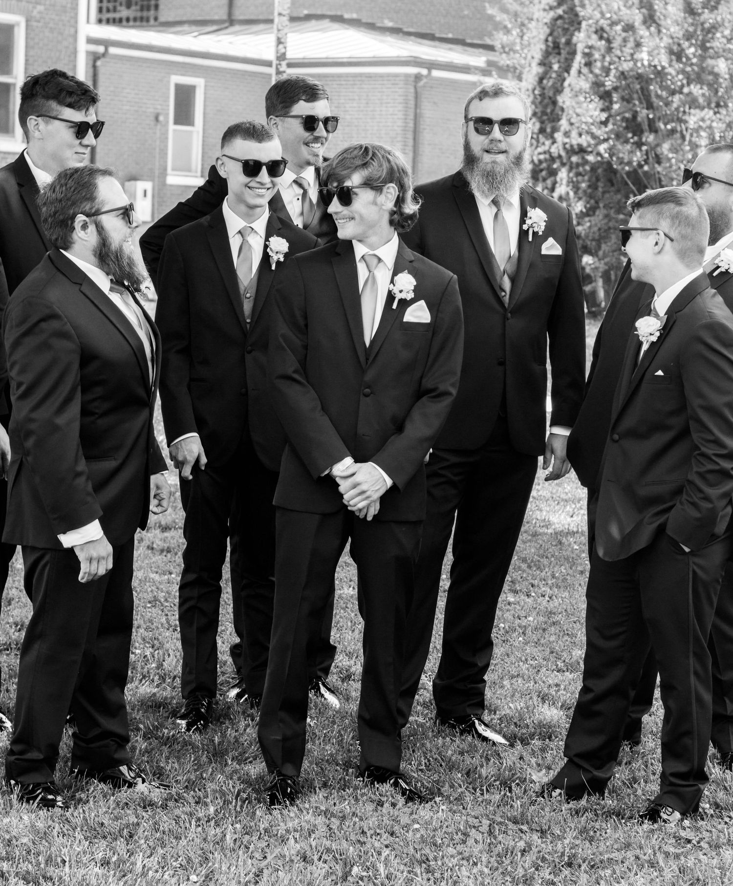 Black-and-white portrait of the groom and groomsmen outdoors.
