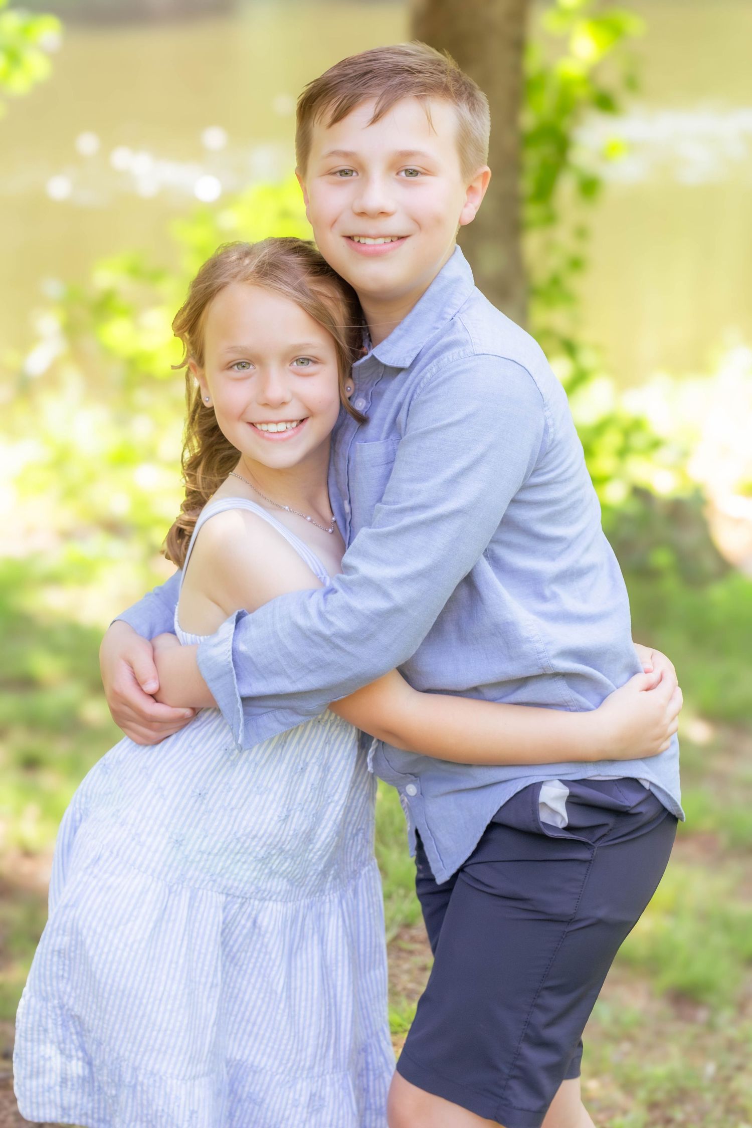 Brother and sister hugging and smiling together outdoors