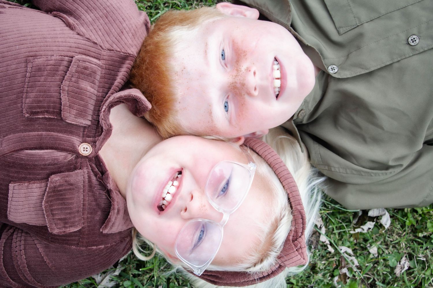 brother and sister laying on the ground posing for picture