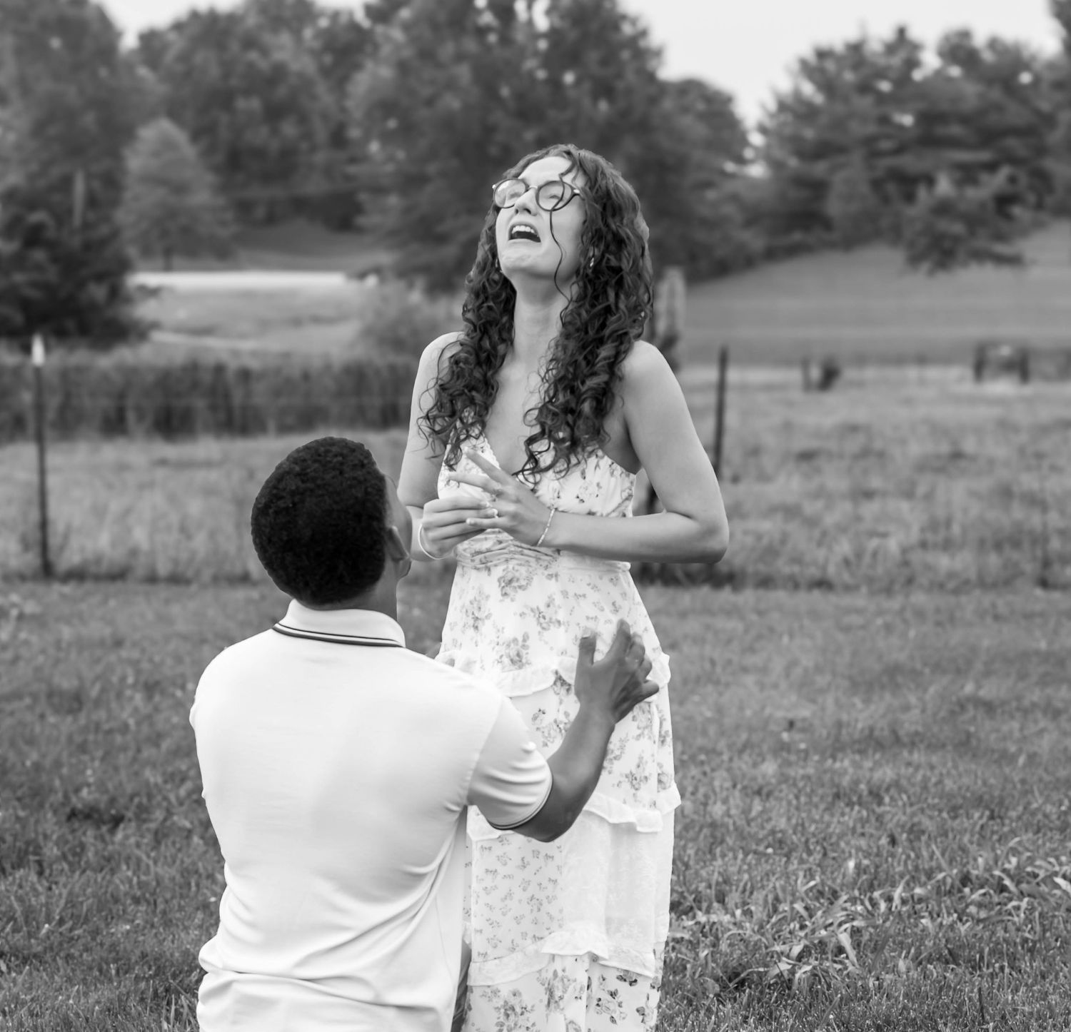 Black-and-white surprise proposal in an open field.