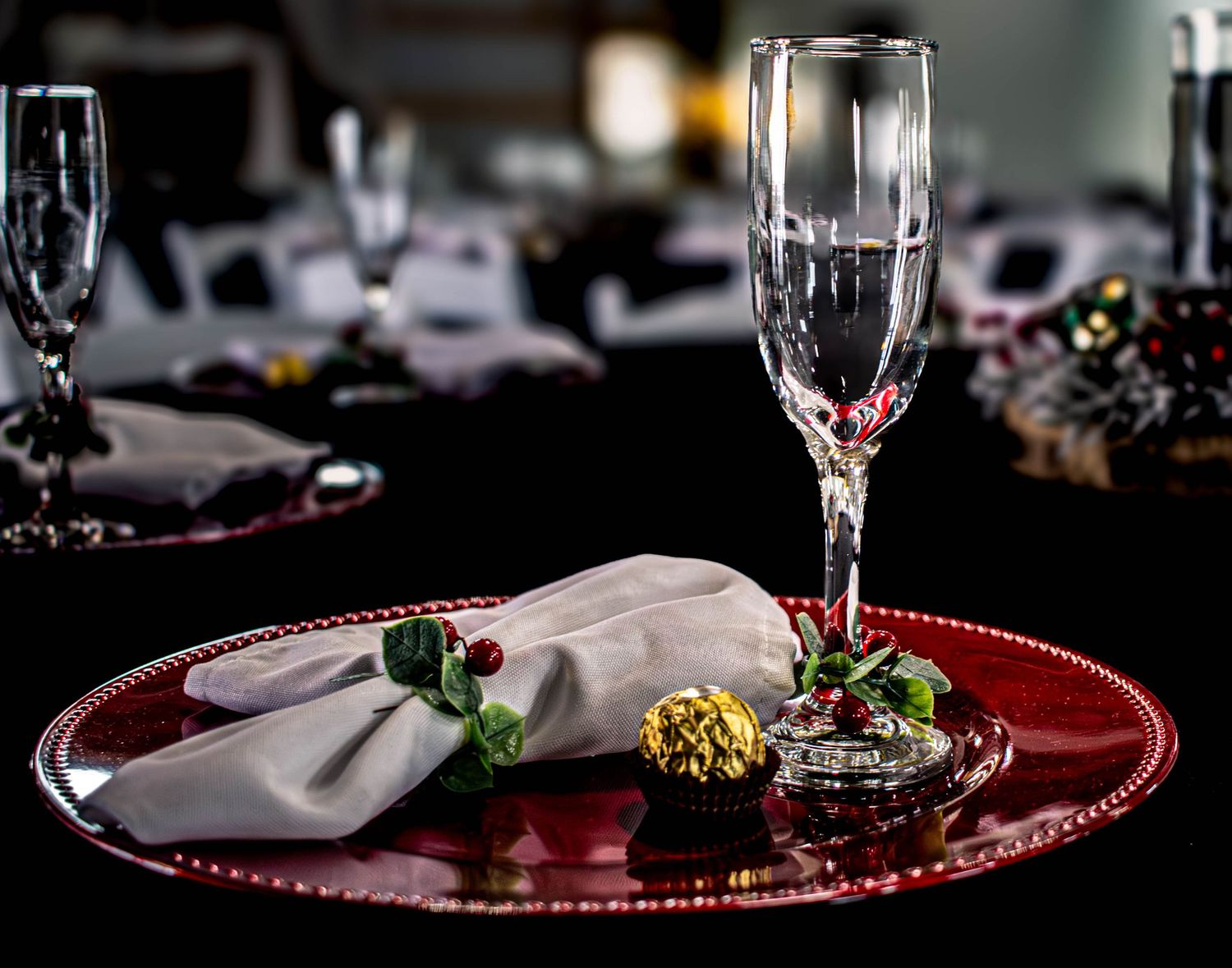 Elegant wedding place setting with champagne glasses and red accents