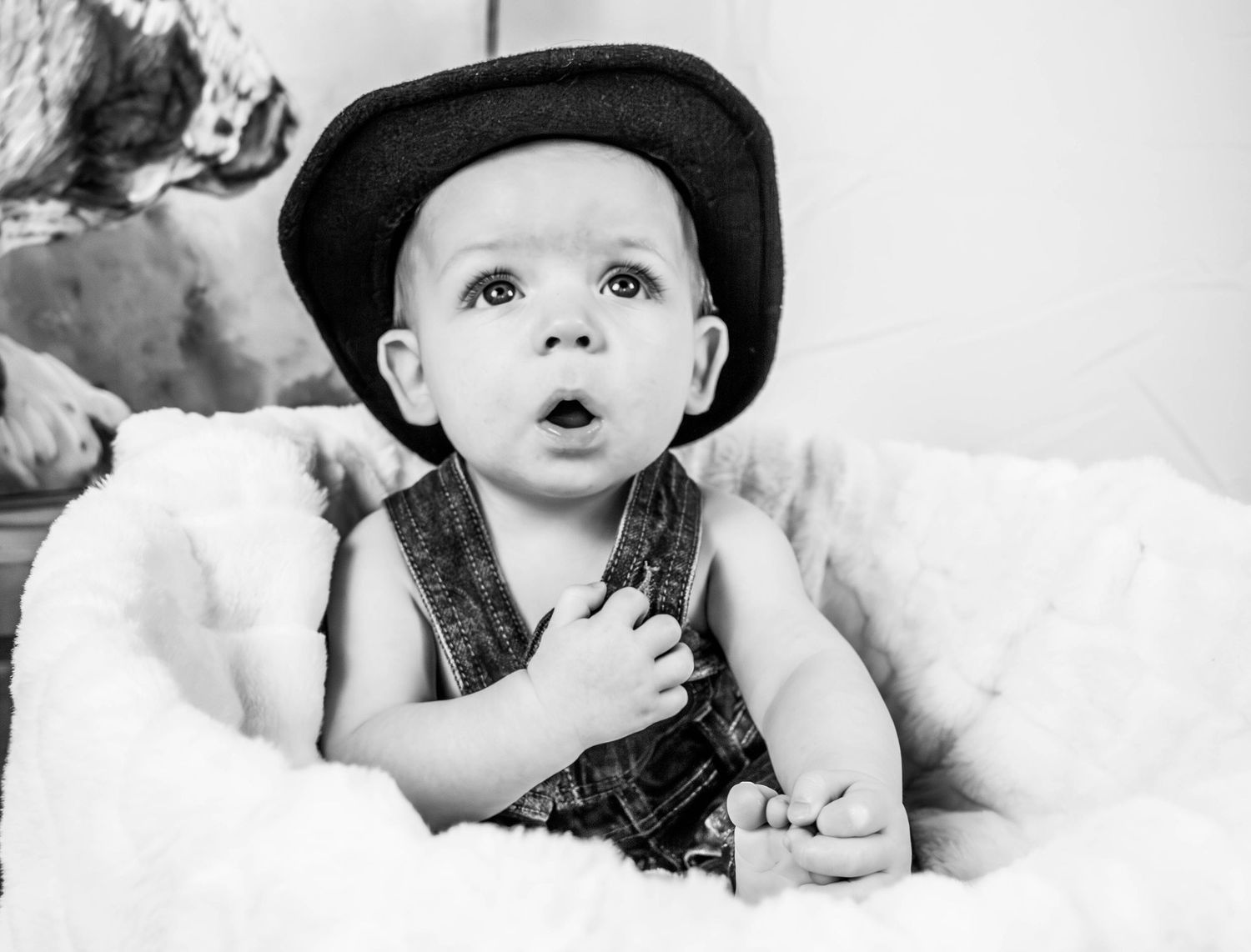 Black-and-white portrait of a baby wearing a cowboy hat.