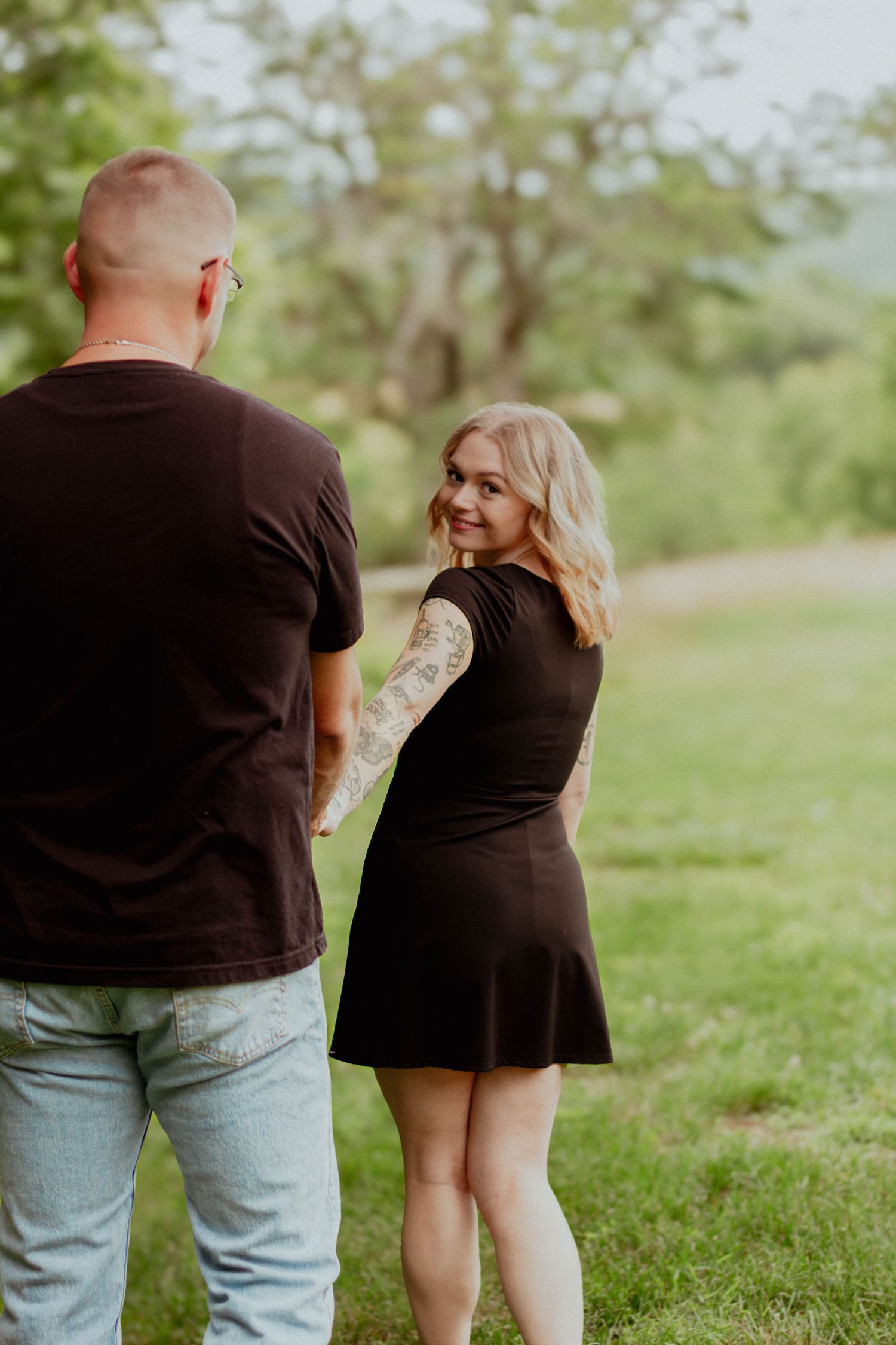 Couple holding hands and smiling at each other outdoors.
