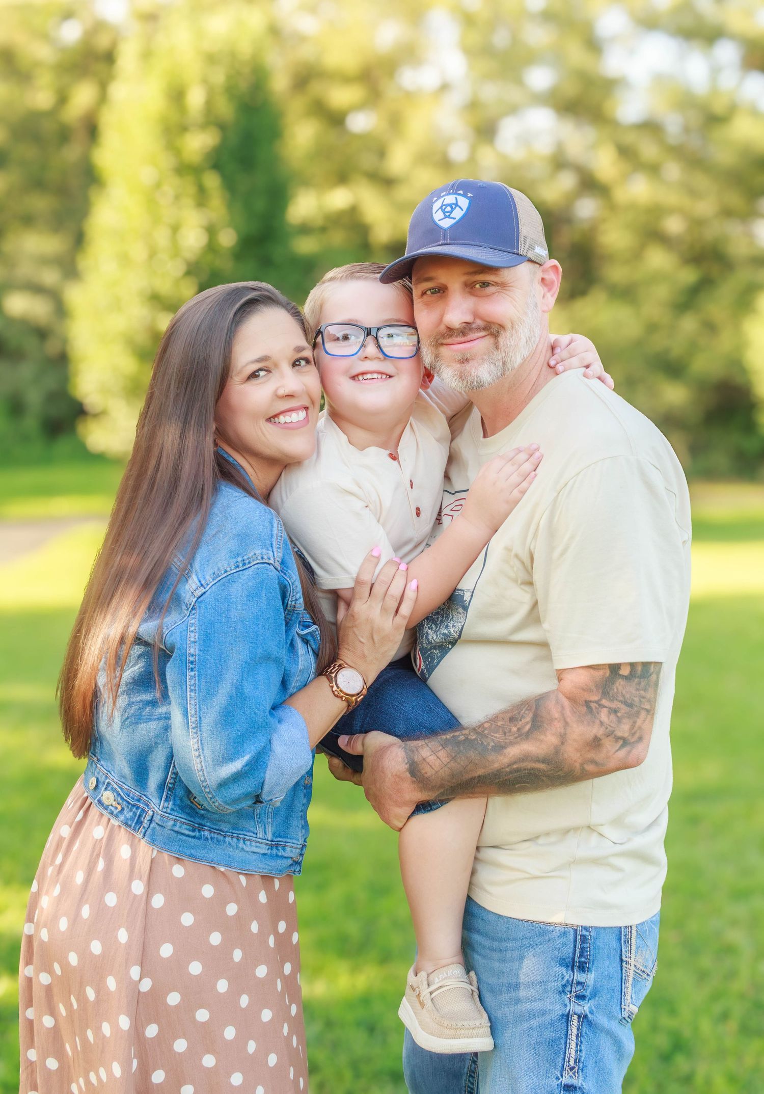 Parents holding their smiling son together during an outdoor family session