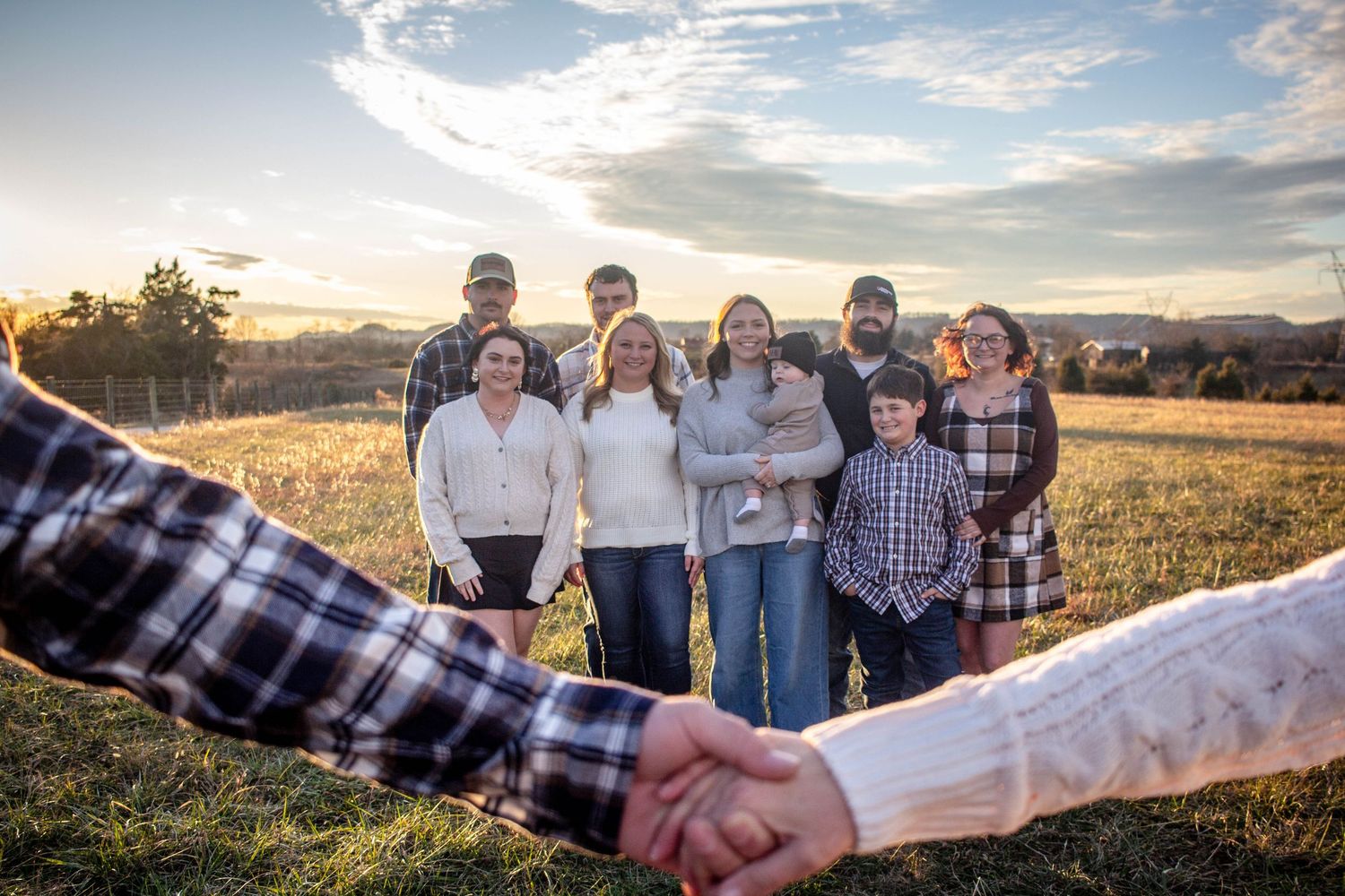 Large family posing together in a field at sunset