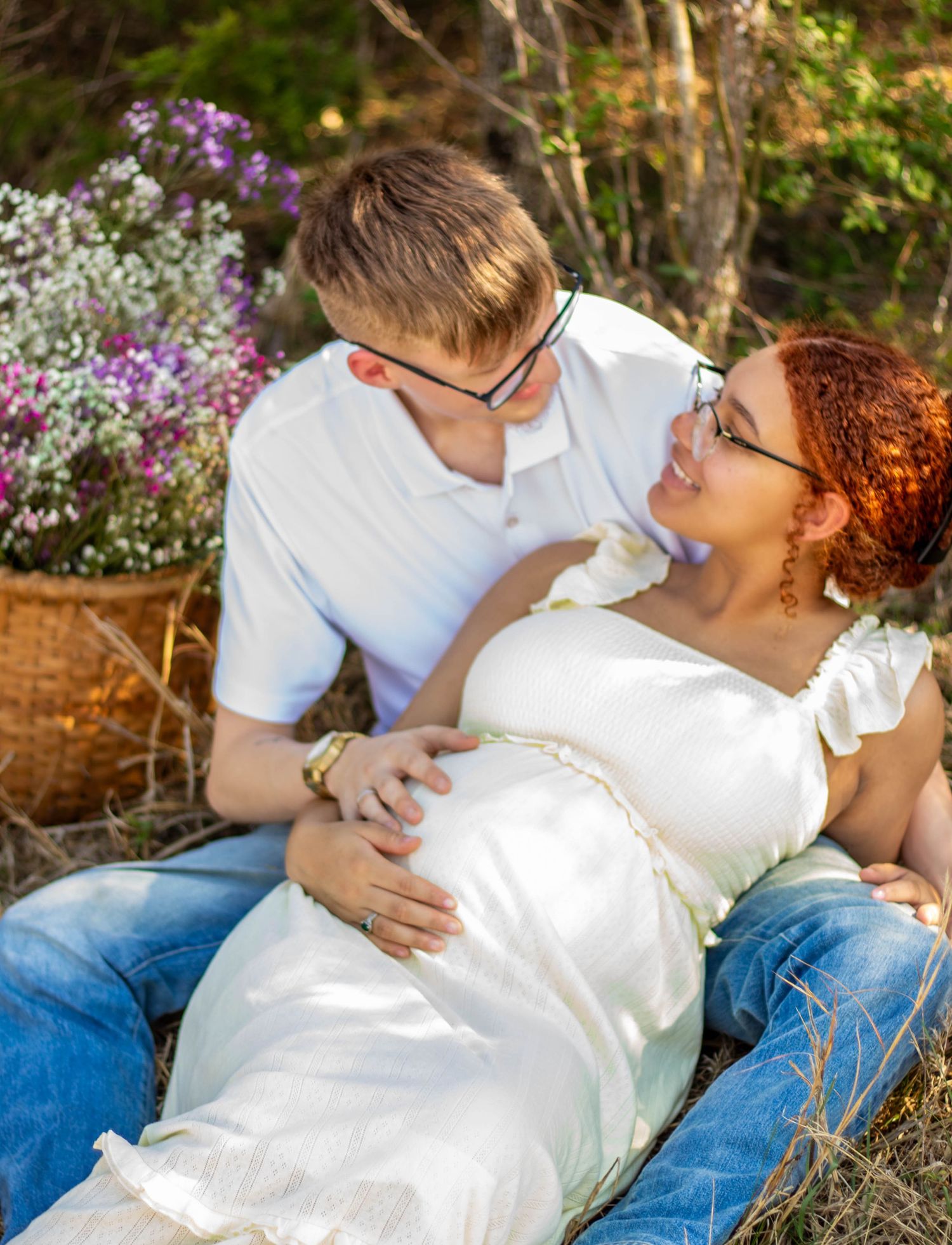 Expecting couple relaxing together outdoors during a maternity session.