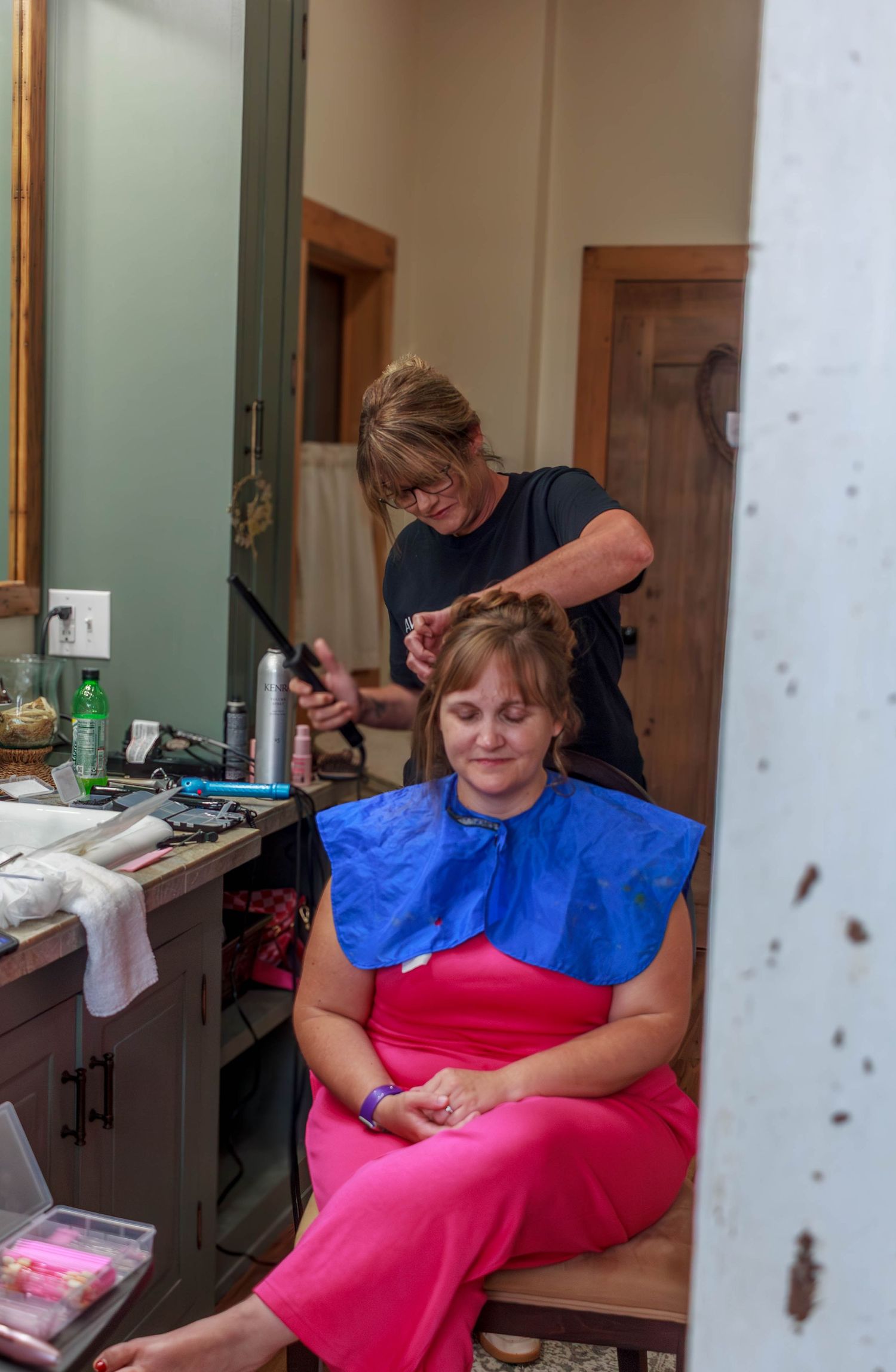 Wedding hairstylist curling and styling hair for a wedding.