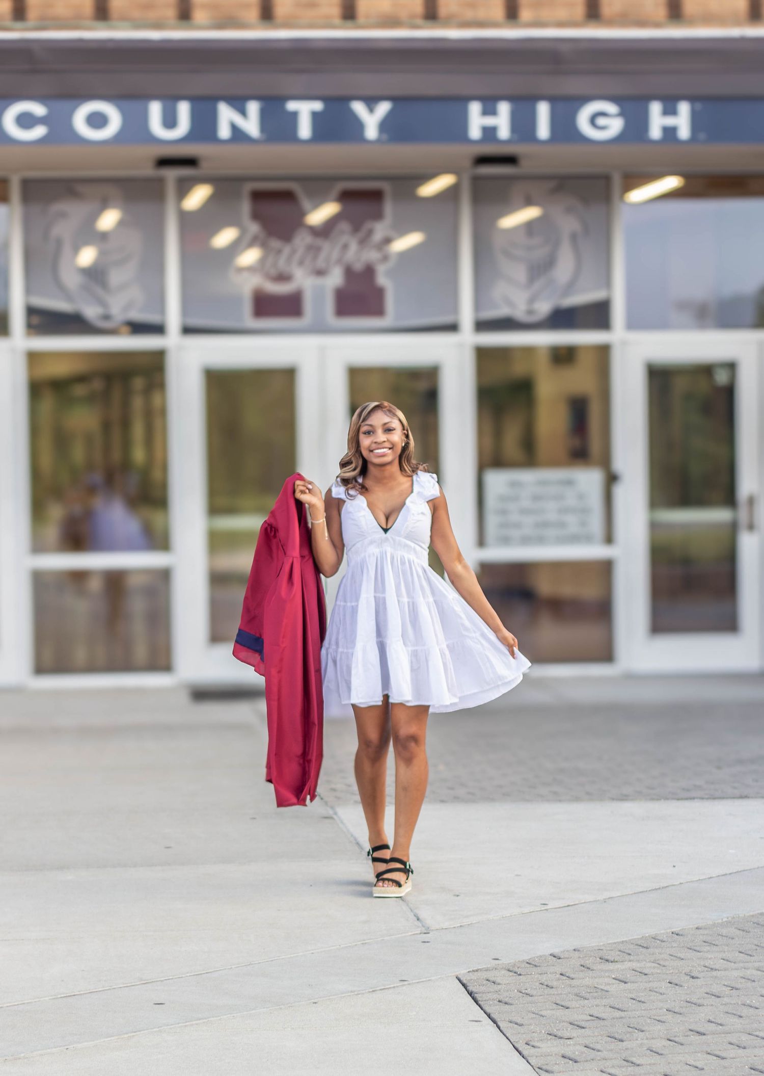 High school senior girl posing outdoors for a senior portrait session in cap and gown