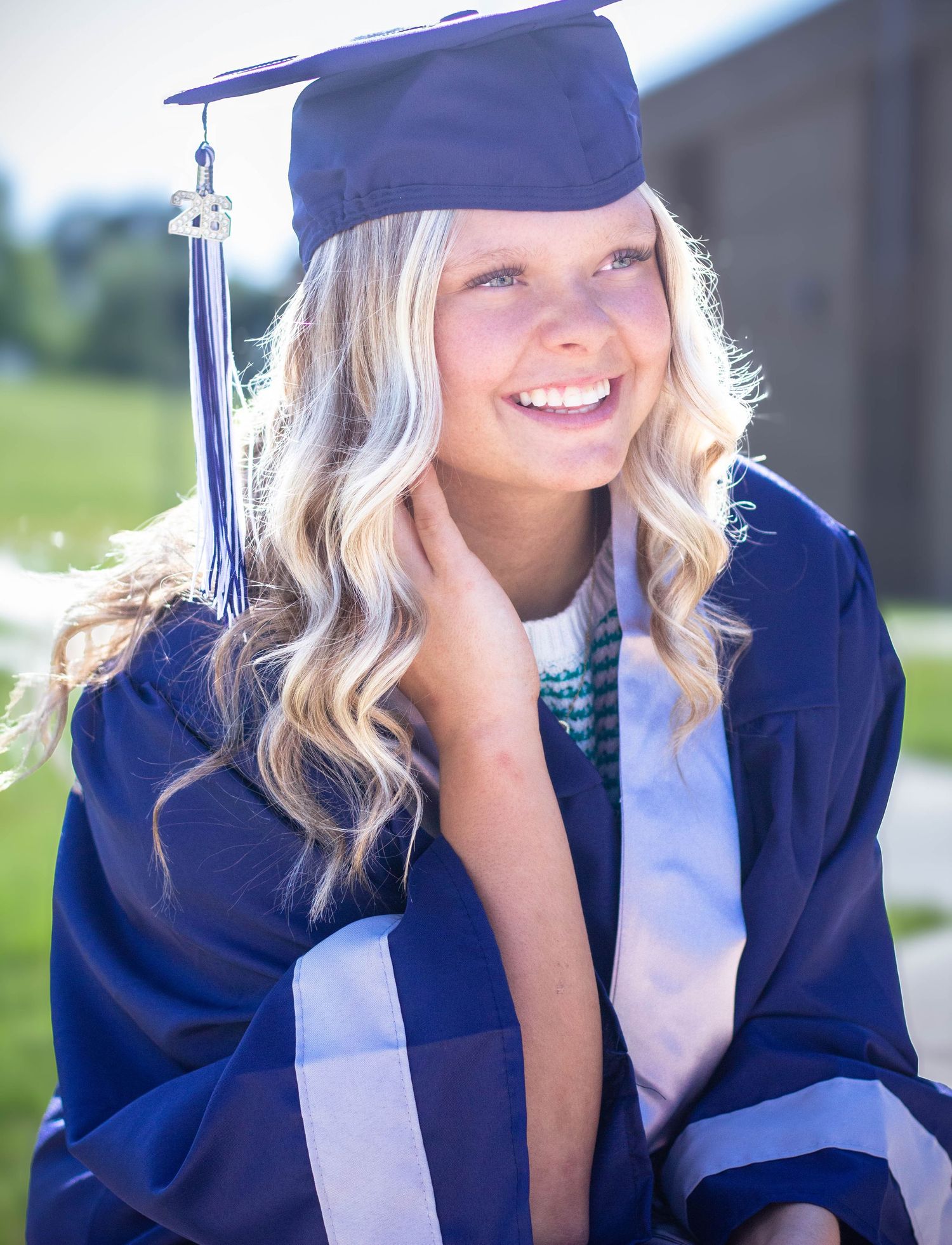 High school senior girl posing outdoors for a senior portrait session in cap and gown