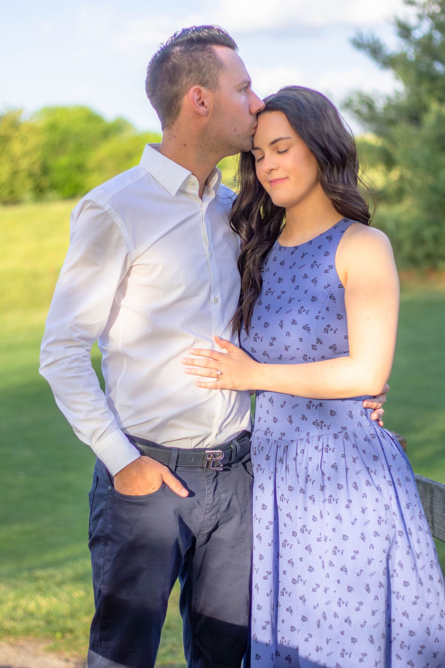 Couple posing together during a sunny outdoor engagement session.