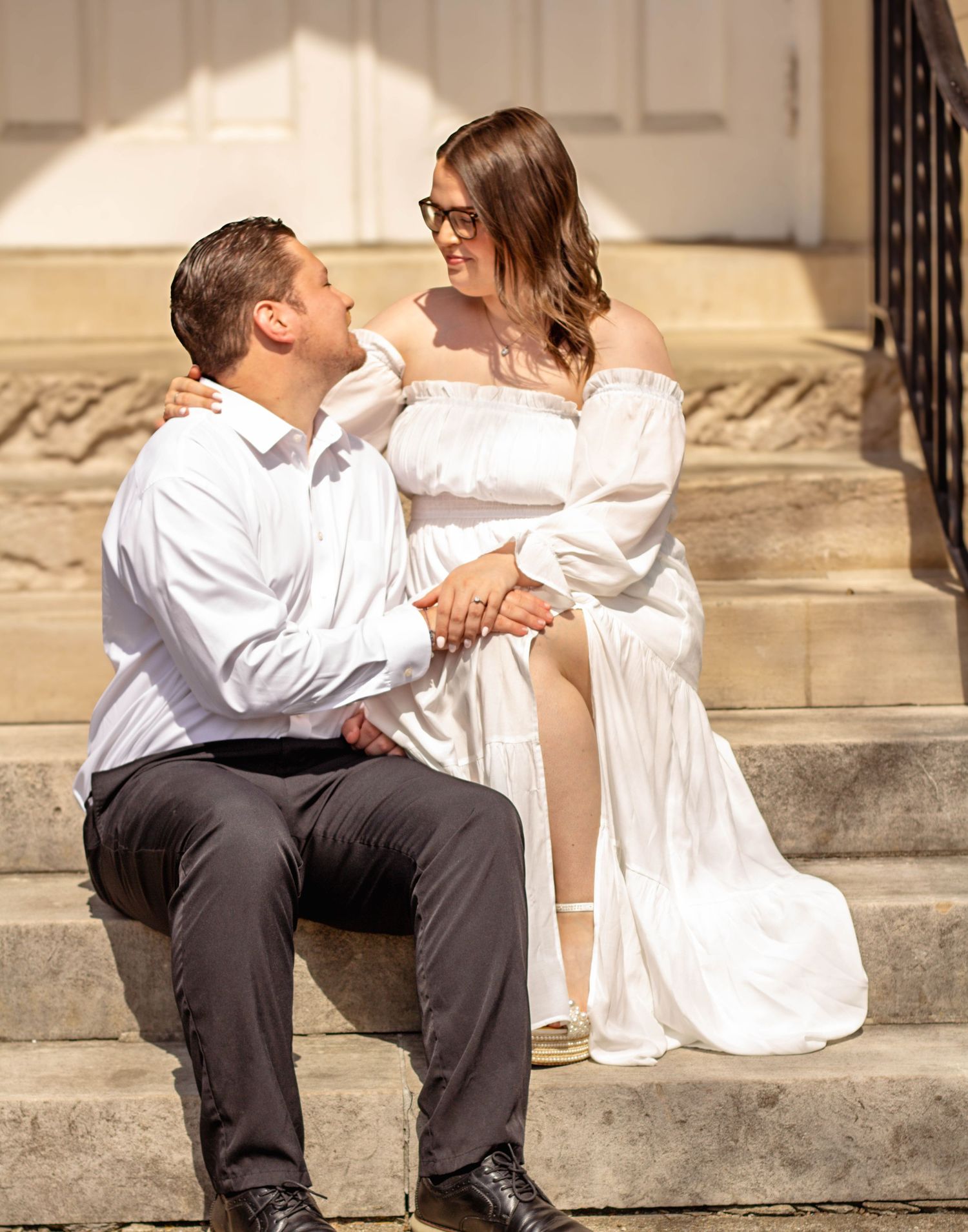 Couple sitting together on outdoor steps during an engagement session.