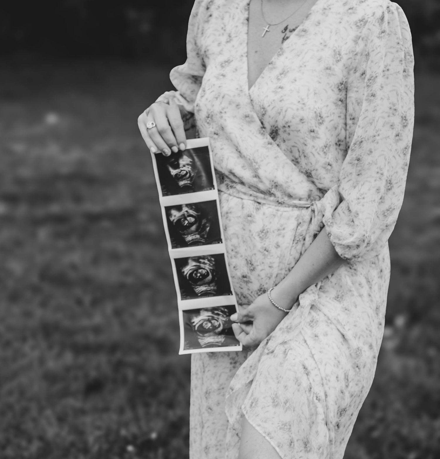 Black-and-white close-up of an expectant mother holding ultrasound photos.