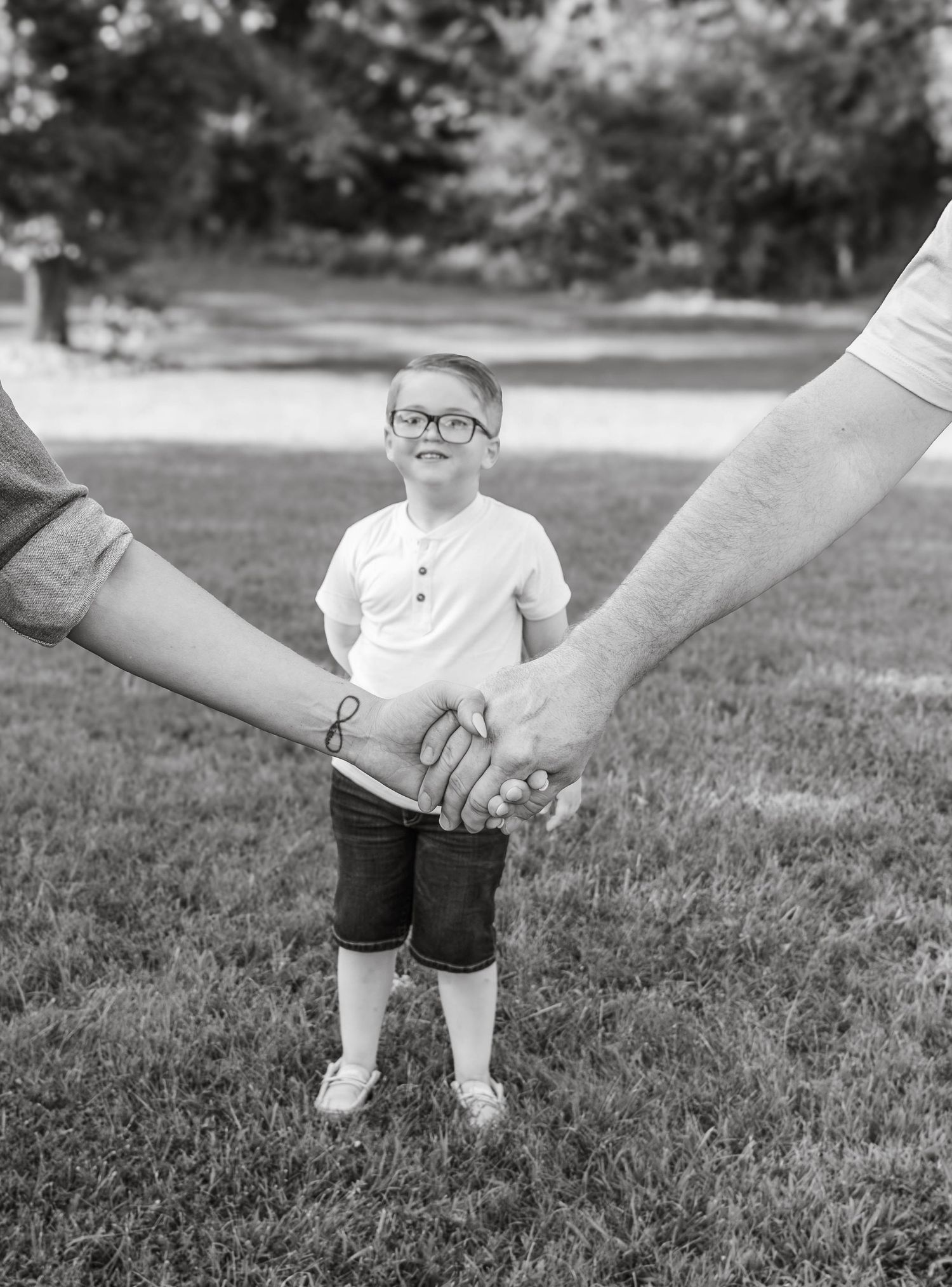 young child standing between two adults holding hands in a black-and-white family photo