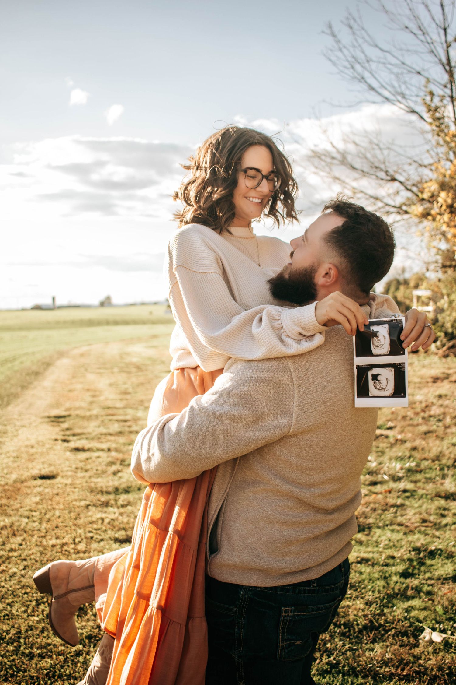 Expecting father lifting the mother during a playful pregnancy announcement portrait.