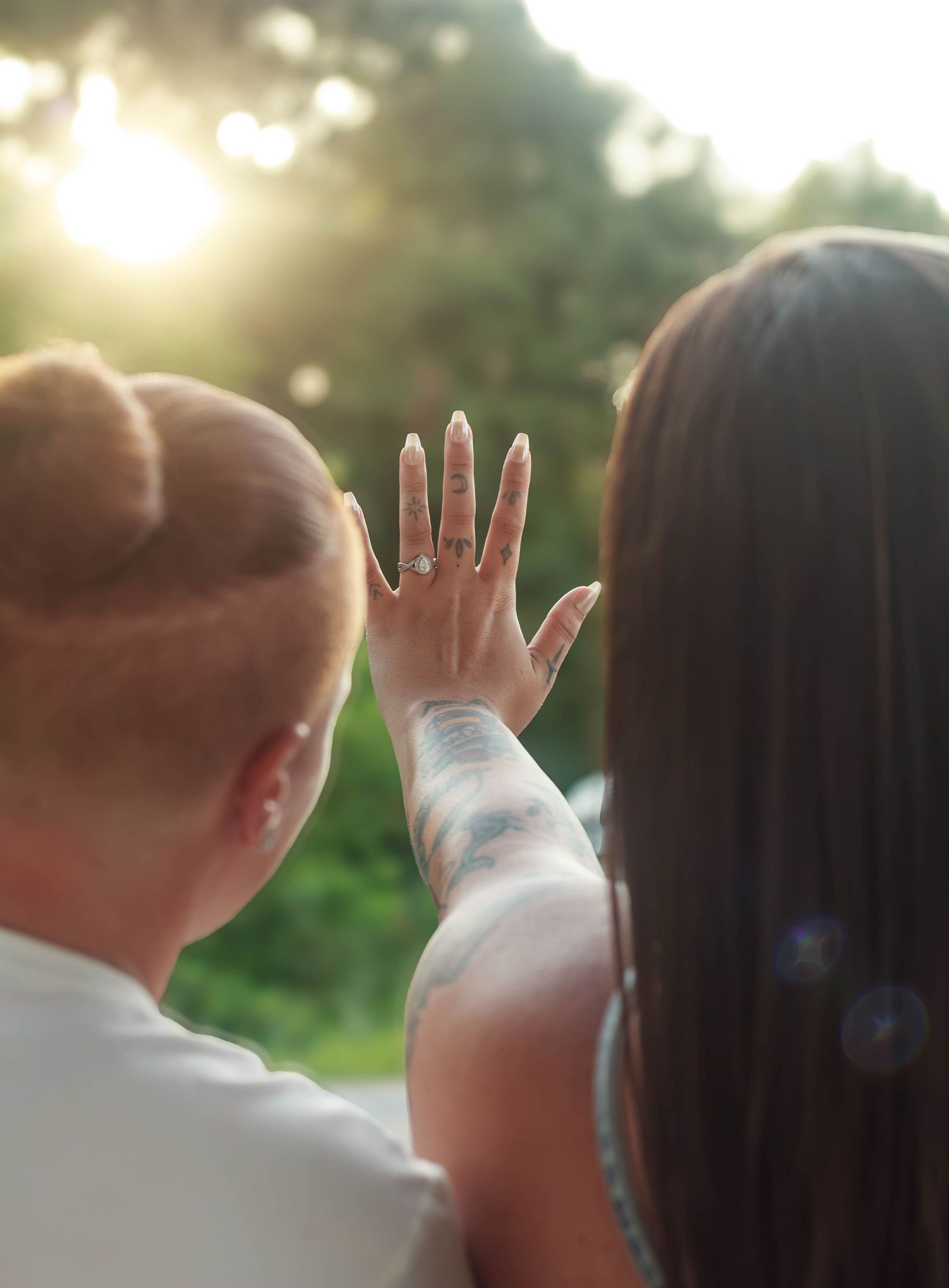 Newly engaged couple showing an engagement ring in the sunlight.