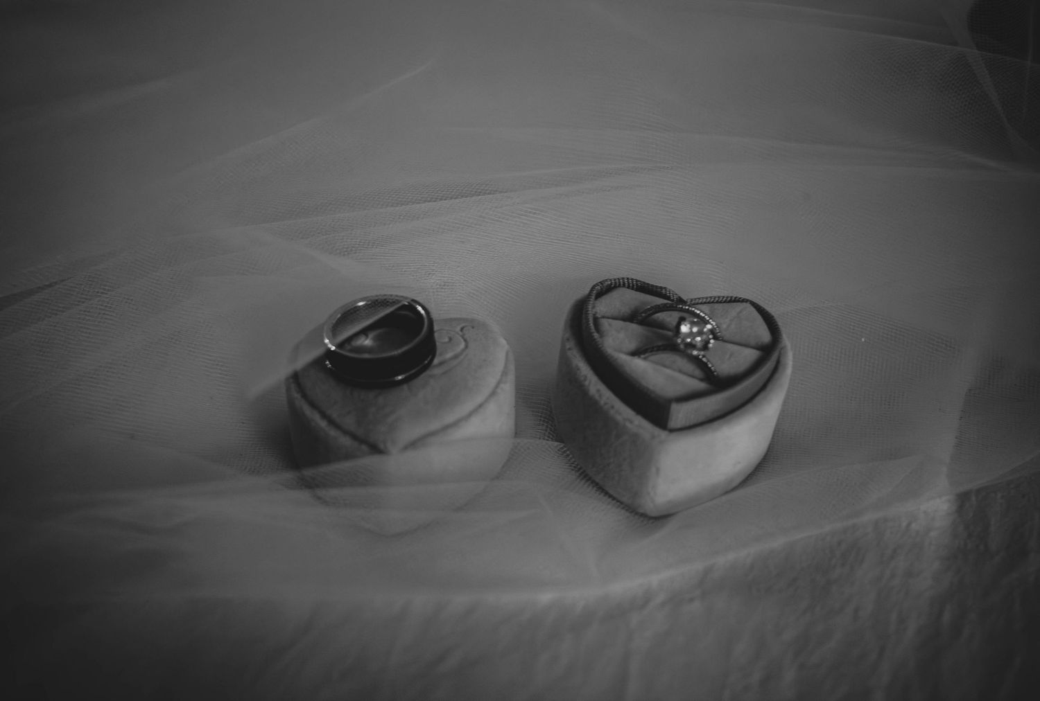 Black-and-white close-up of wedding rings resting on fabric.
