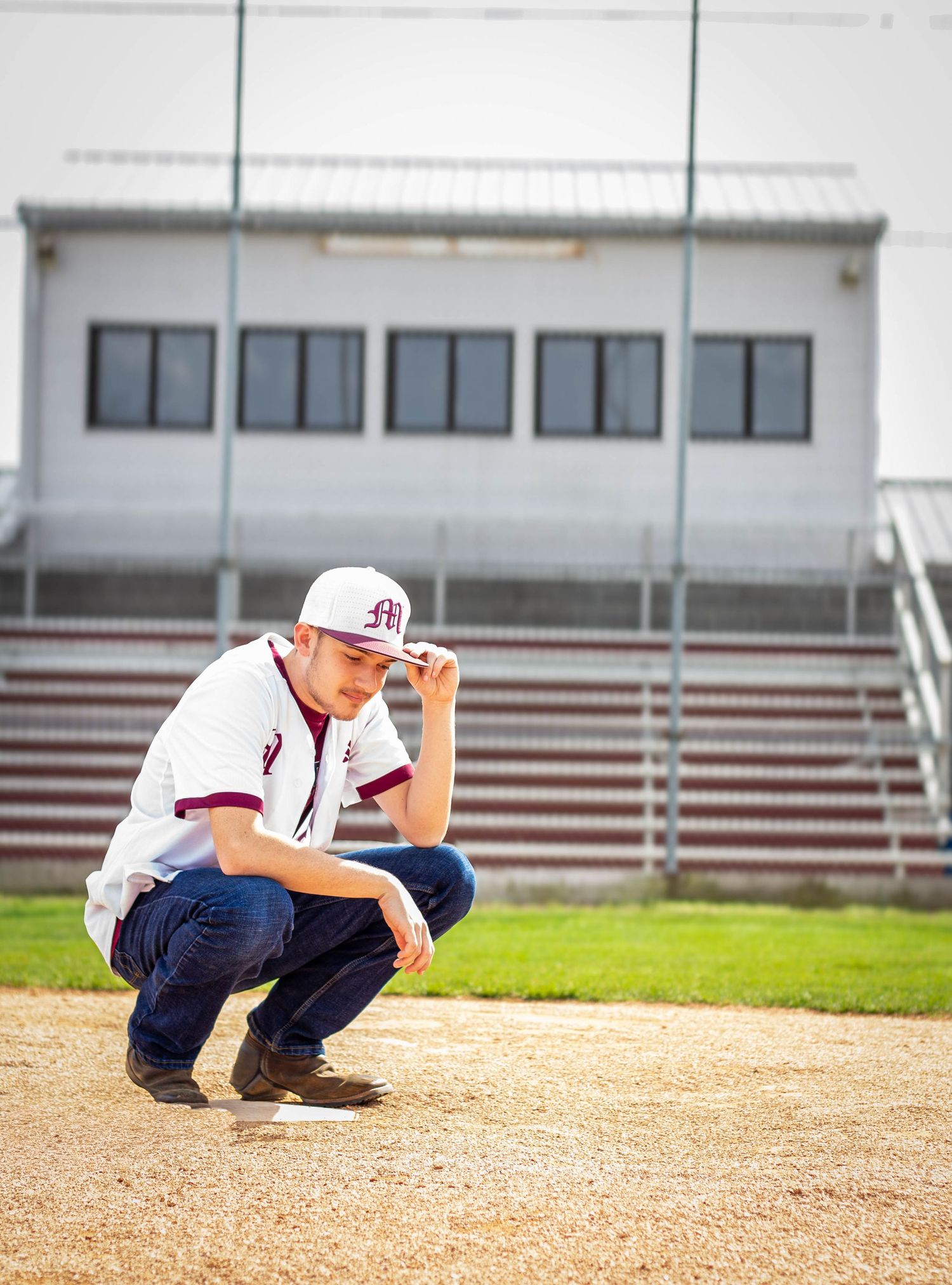 High school senior boy baseball player posing outdoors for a senior portrait session on baseball field in jersey