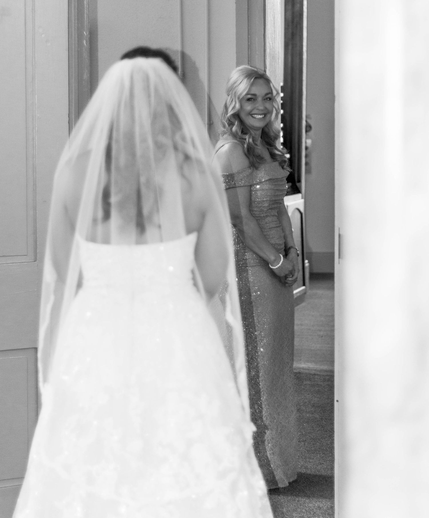 Black-and-white photo of a bride seeing herself in her wedding dress.