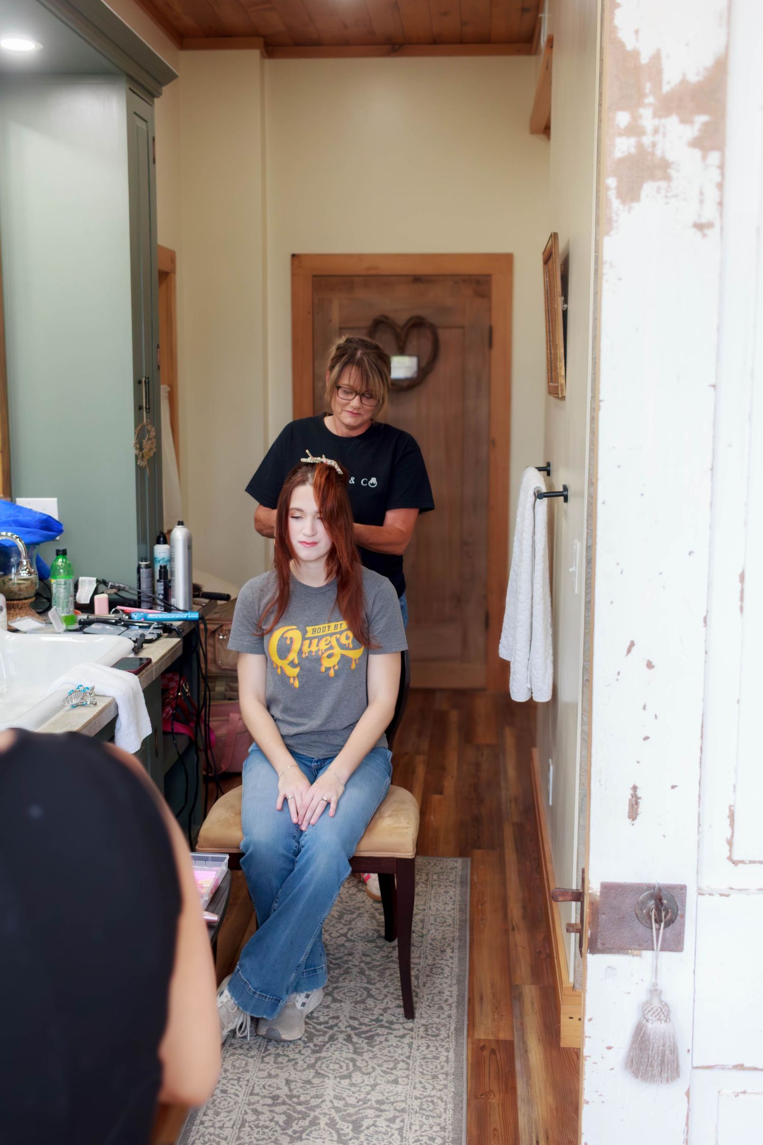 Wedding hairstylist styling a bridal party member's hair while getting ready.