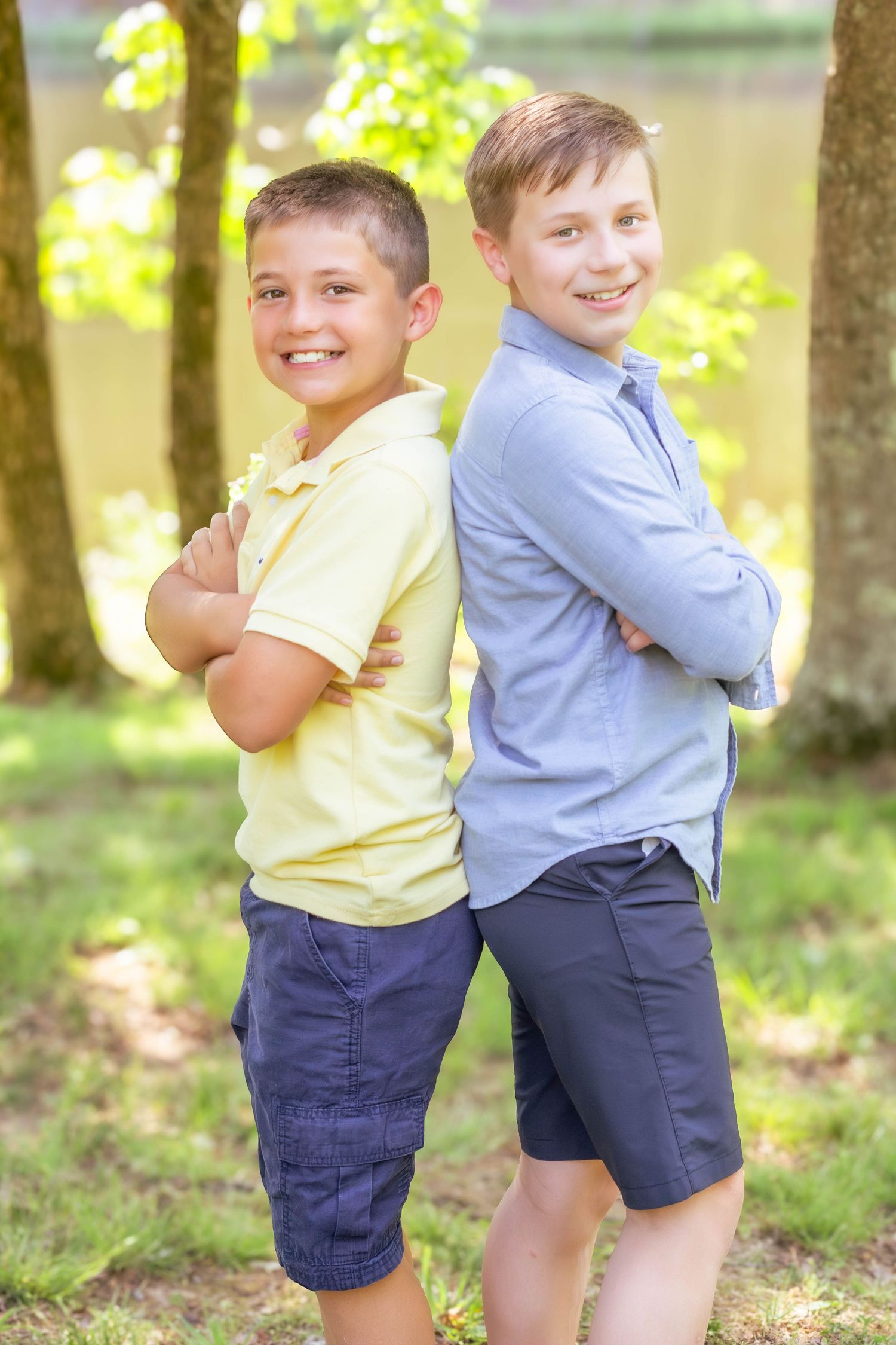 Two brothers posing back-to-back and smiling outdoors