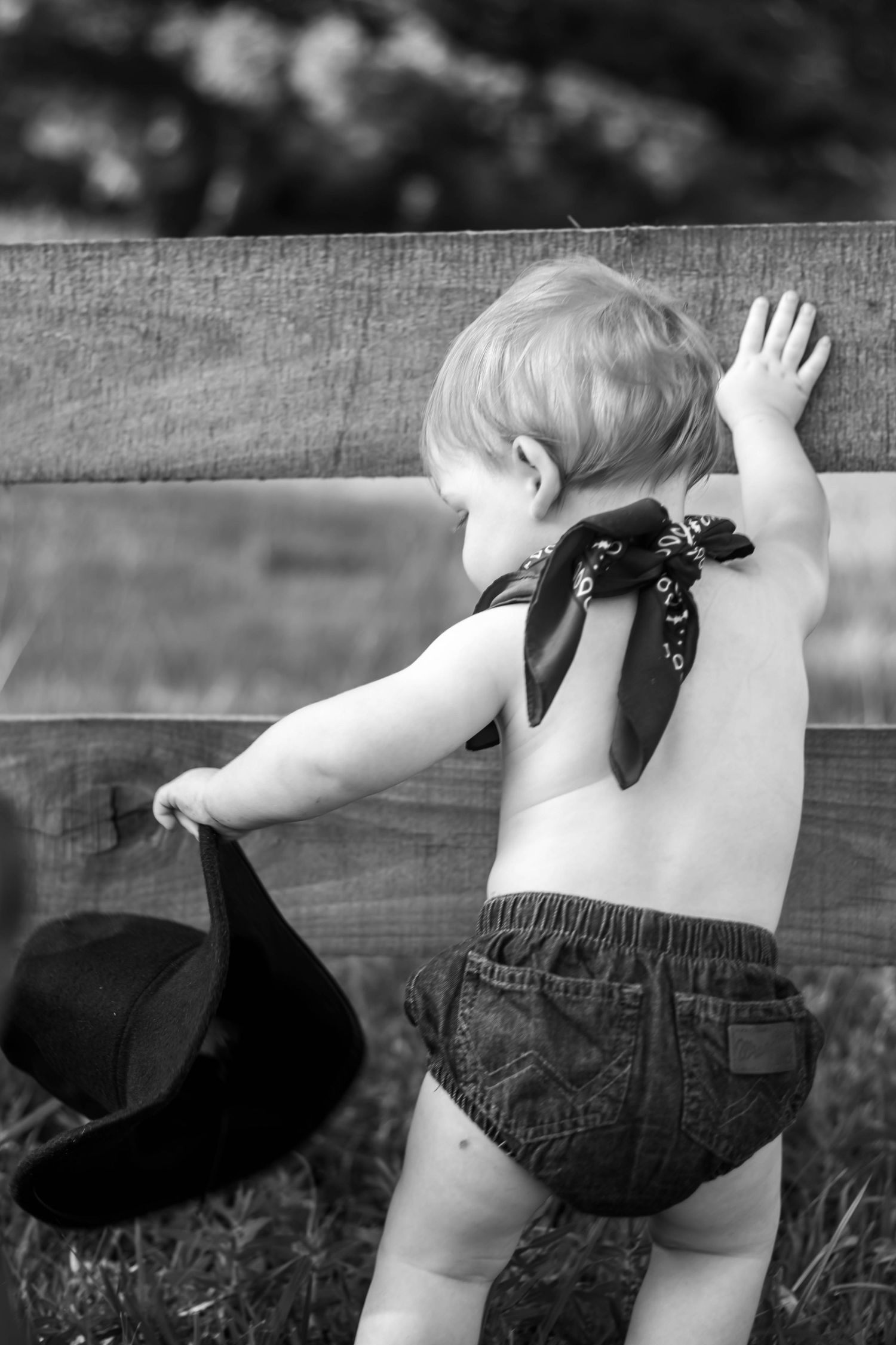 Black-and-white candid of a baby playing with a cowboy hat.