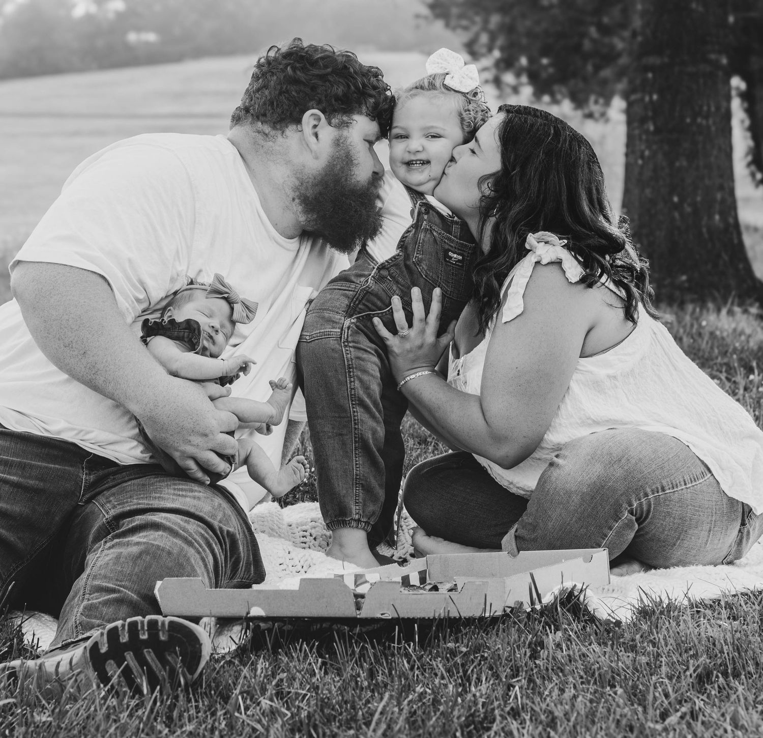 Parents cuddling and kissing their young daughter during an outdoor family session