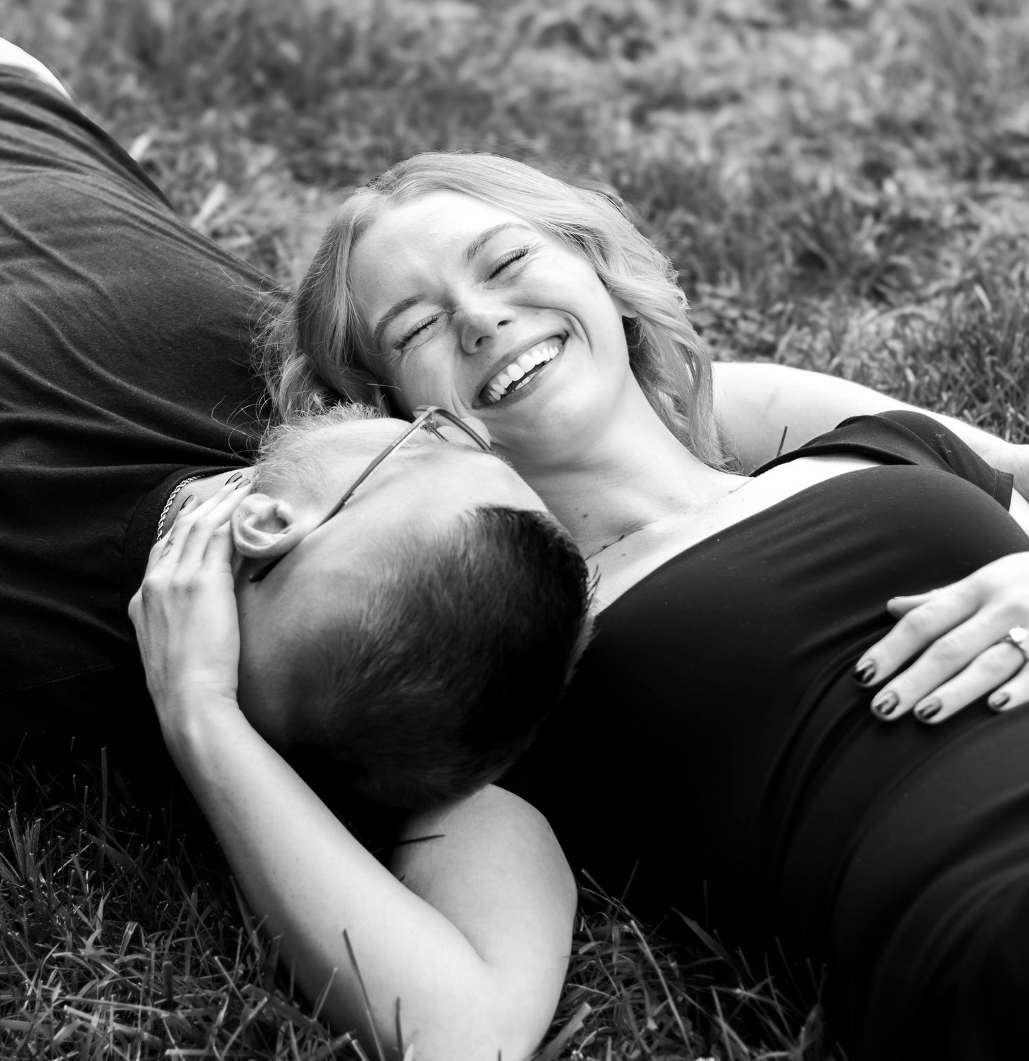 Black-and-white candid of a couple lying together in the grass.