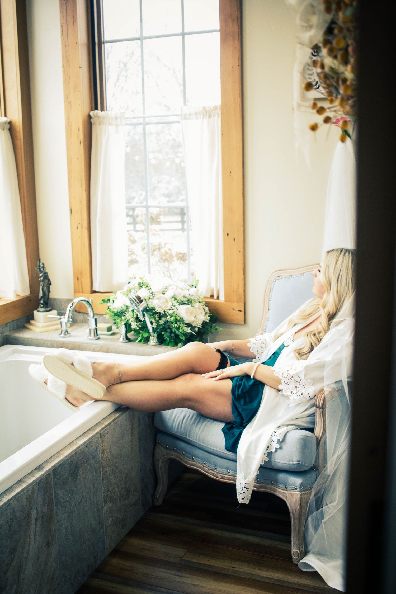 Bride relaxing by a window during wedding day preparations