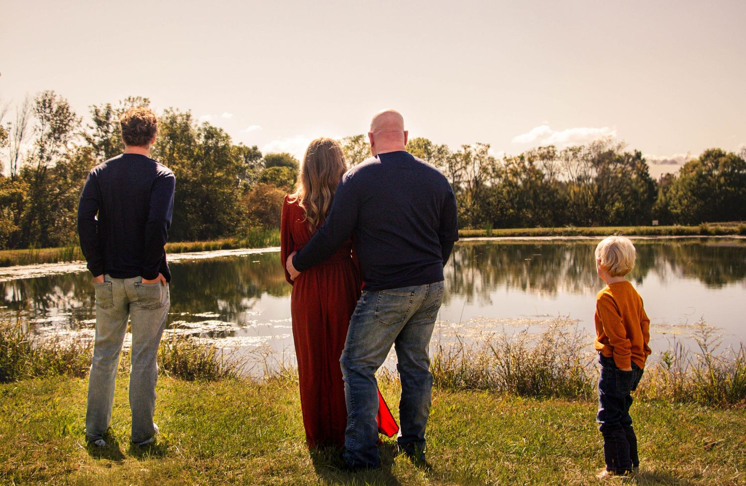 Family walking together beside a pond during a golden-hour photography session