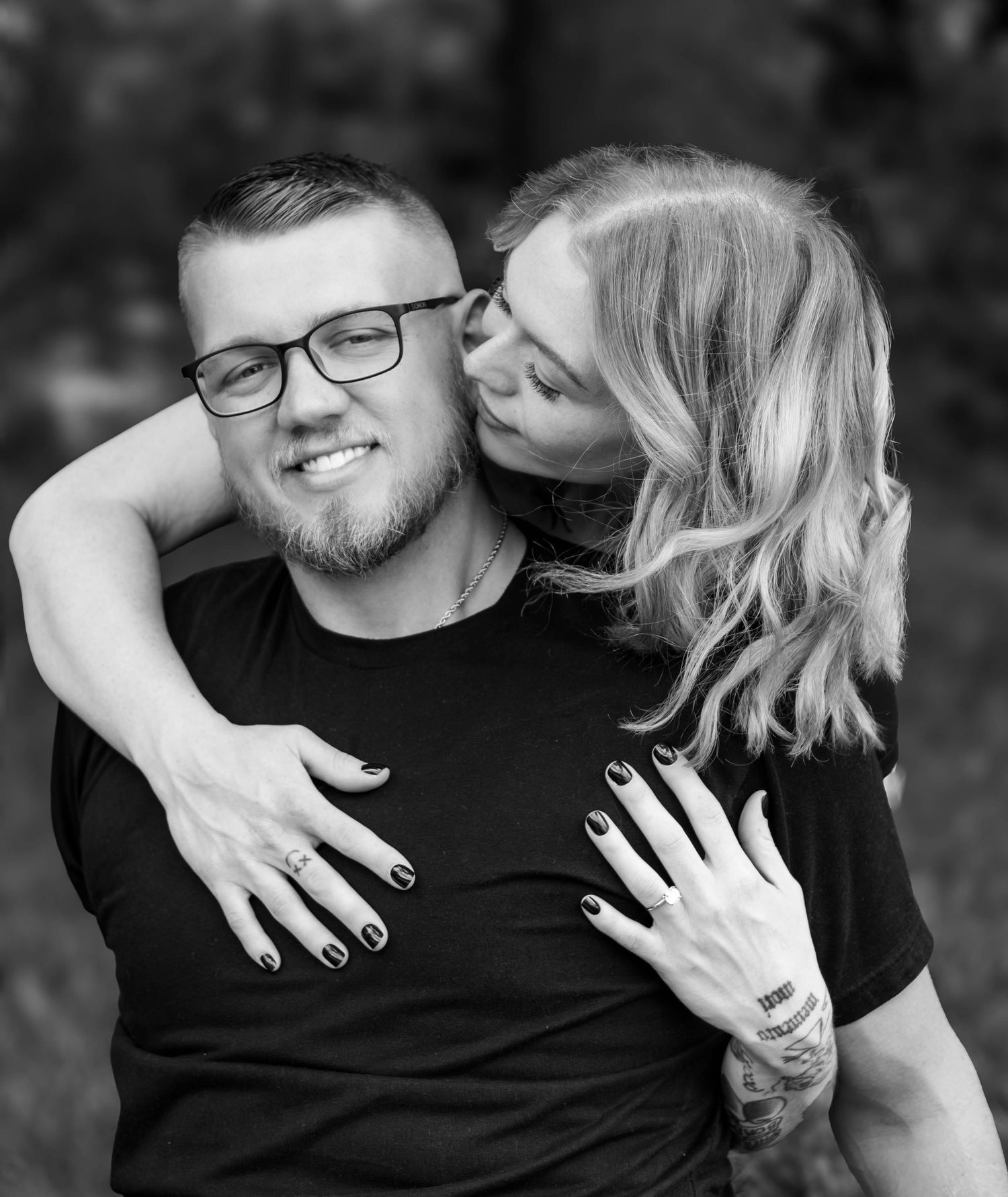 Black-and-white playful portrait of a couple embracing outdoors.