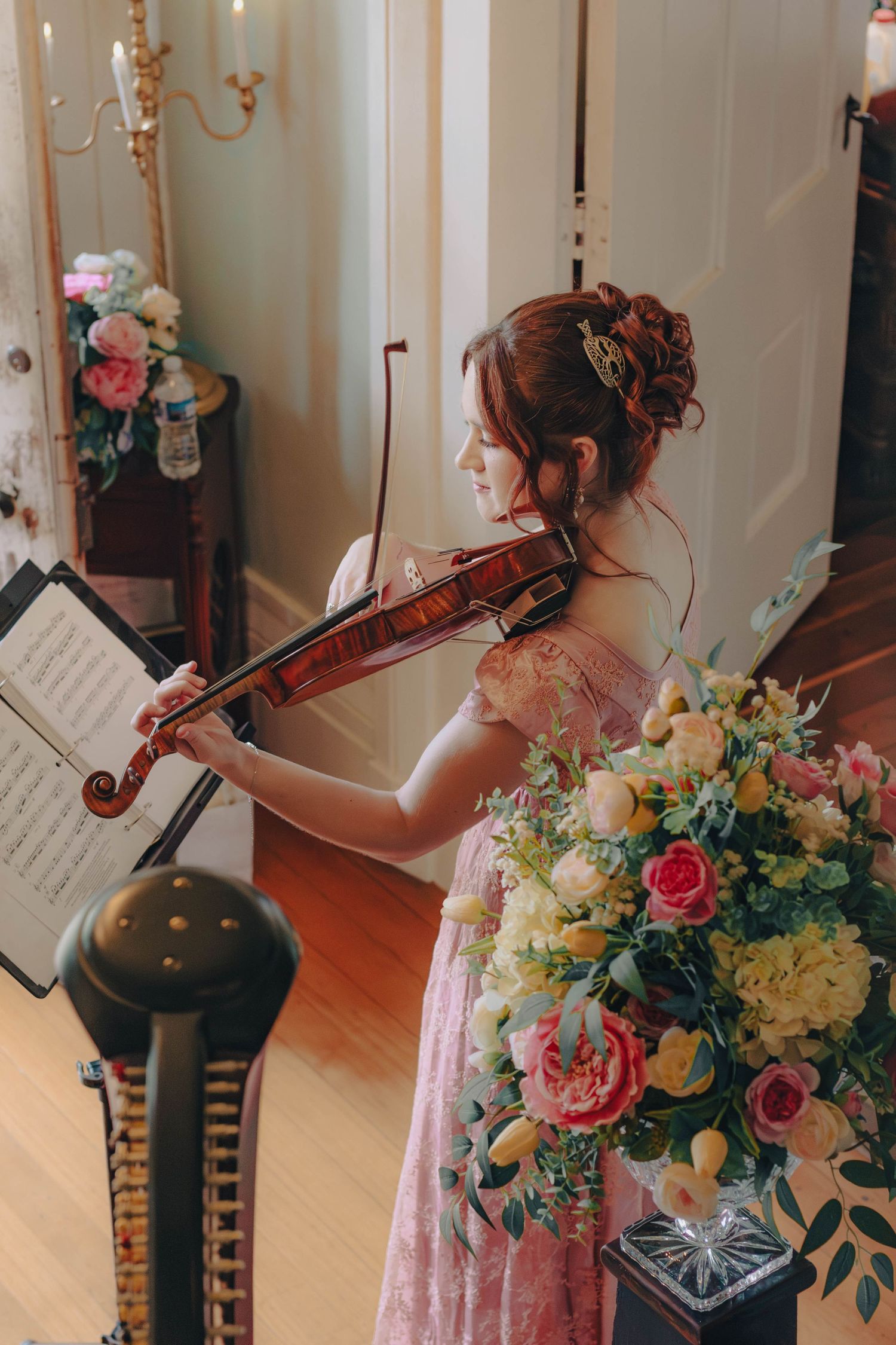 Violinist beside colorful wedding flowers.