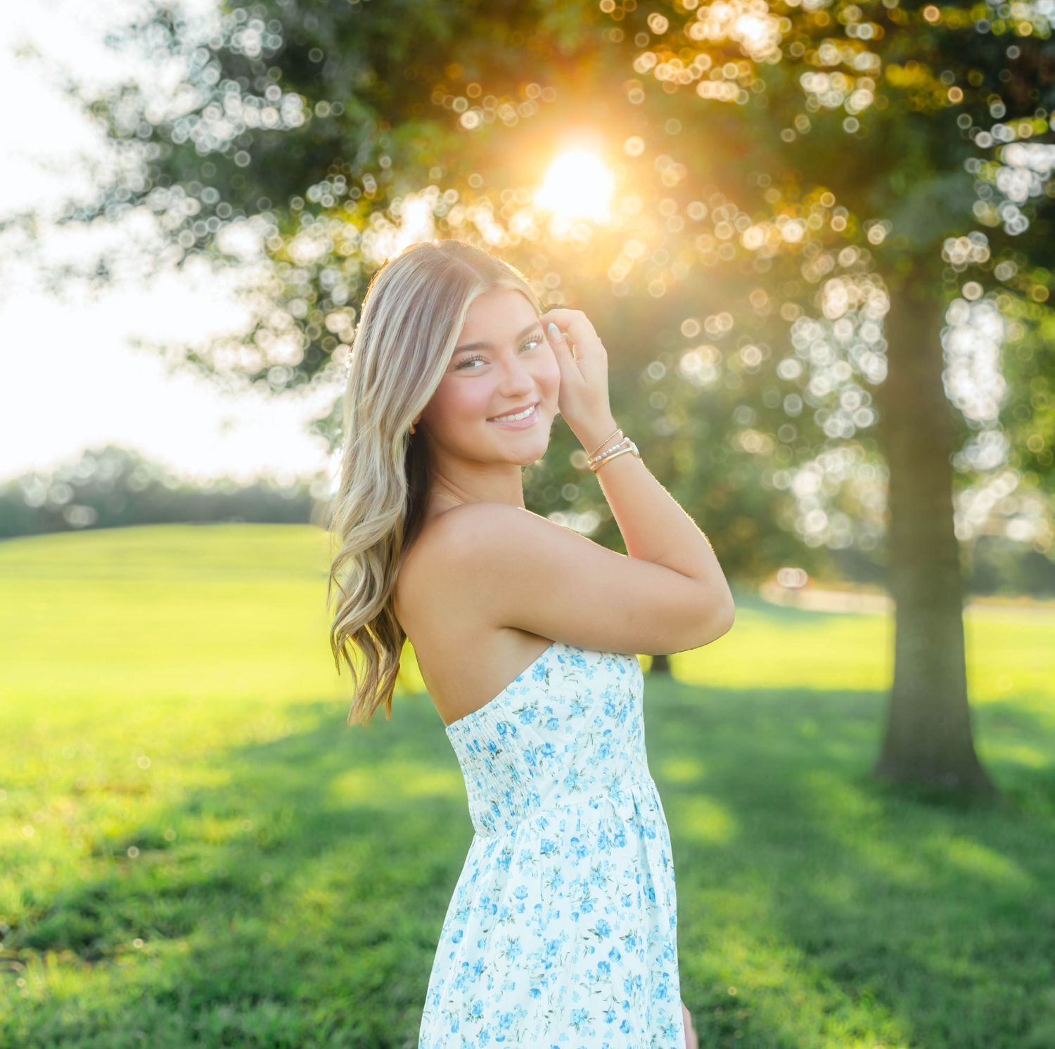 Senior girl posing outdoors in a blue floral dress during a summer senior photography session