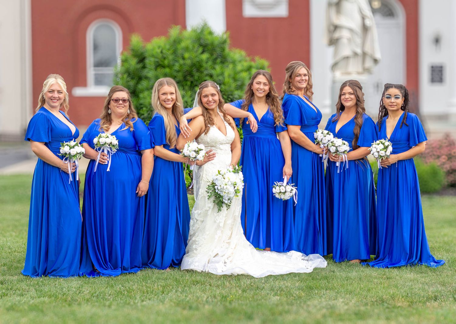 Bride posing with her bridesmaids in bright blue dresses.