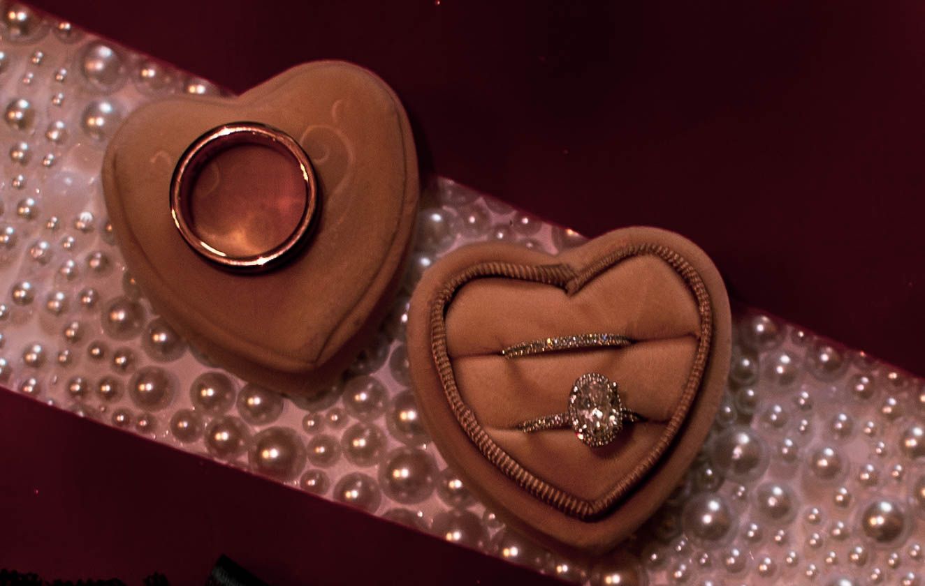 Close-up of heart-shaped wedding accessories on sparkling fabric.