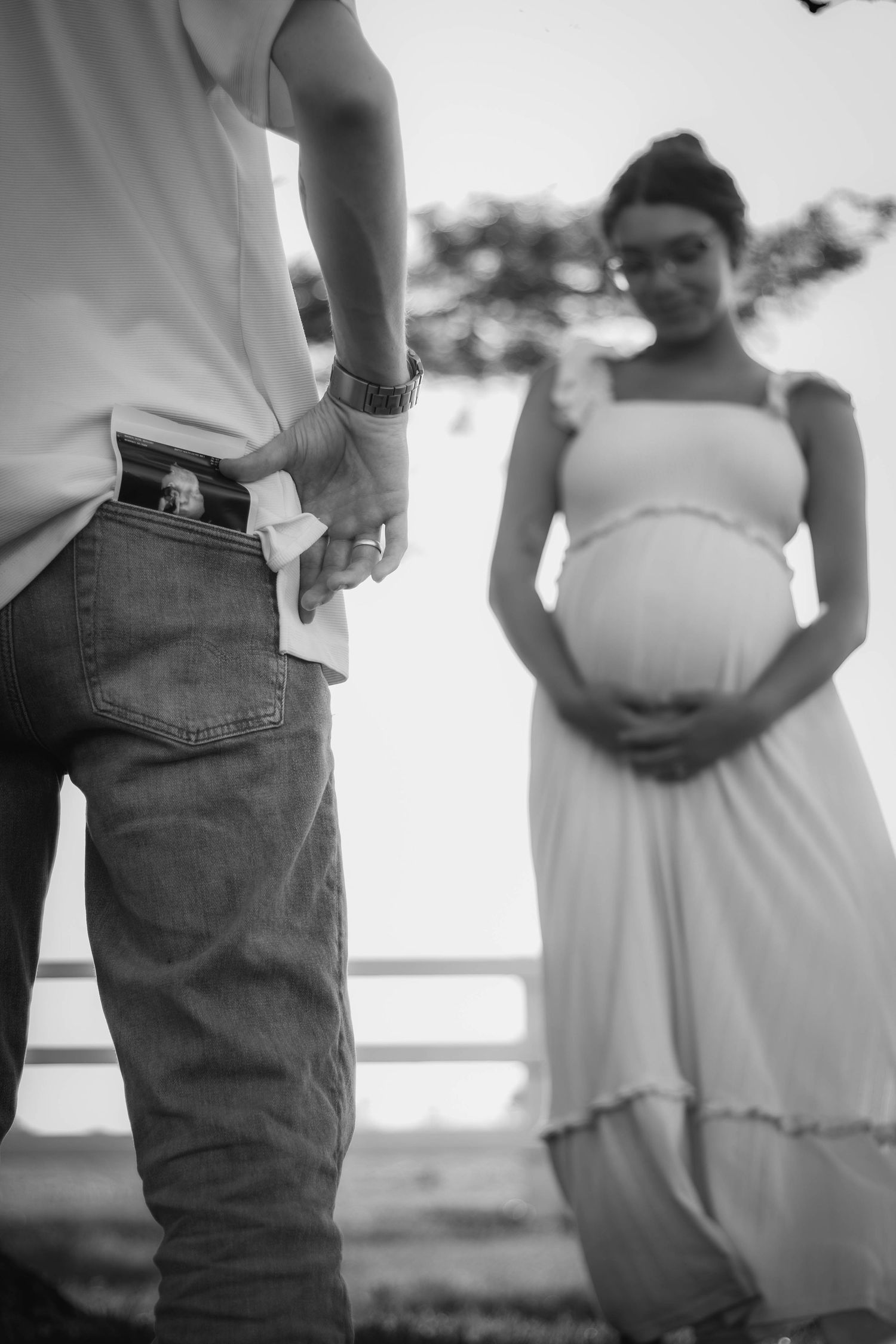 Black-and-white maternity portrait of an expectant mother with her partner beside her.