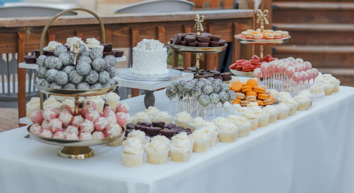 Wedding dessert table filled with cupcakes and sweets.