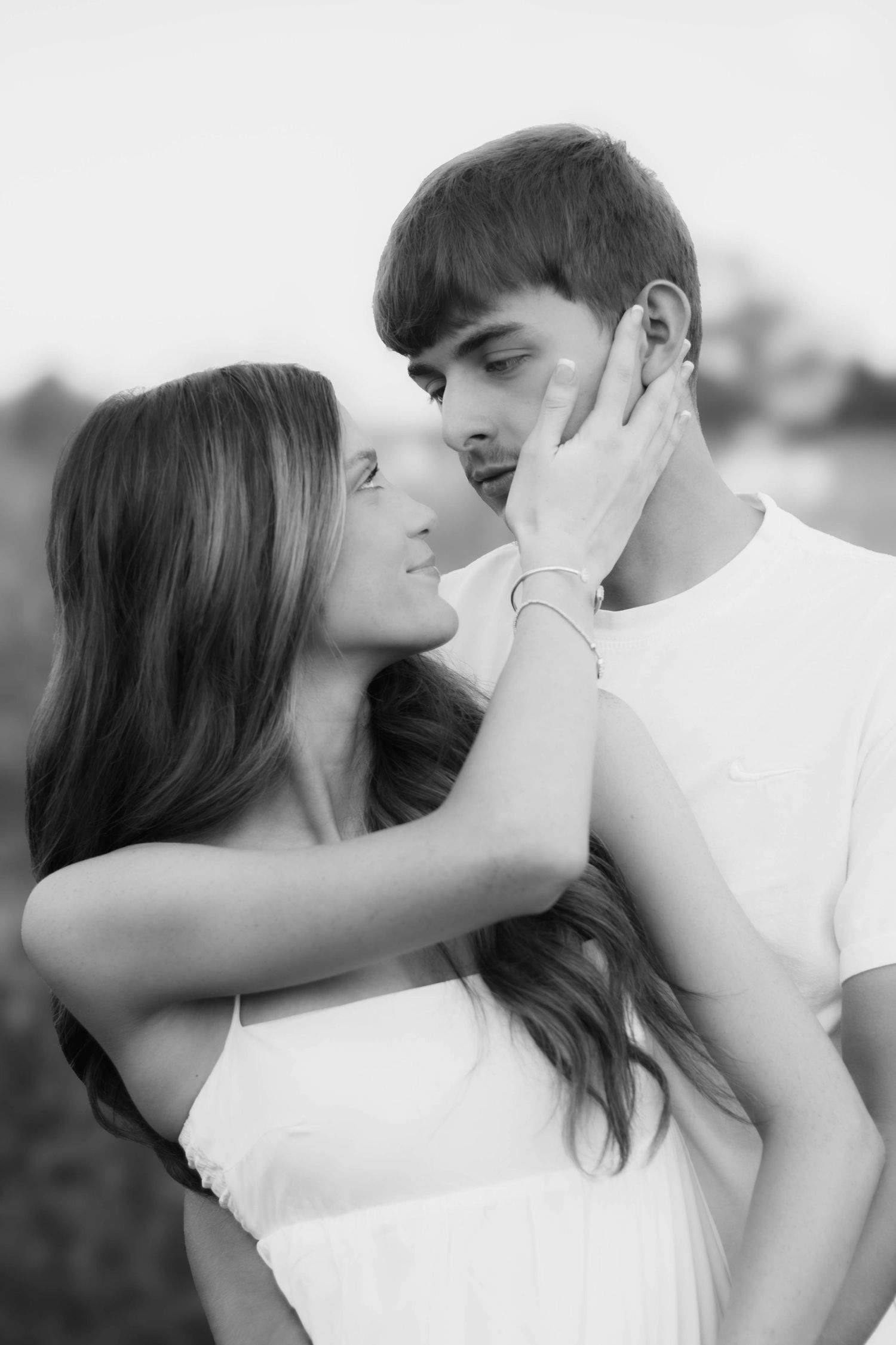 Black-and-white portrait of a couple kissing outdoors.