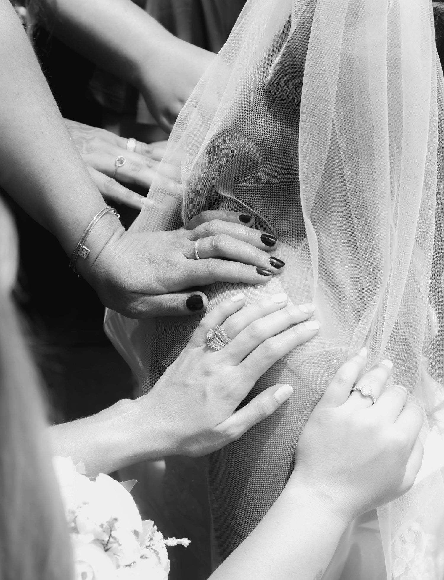 Black-and-white close-up of bridesmaids praying over the bride