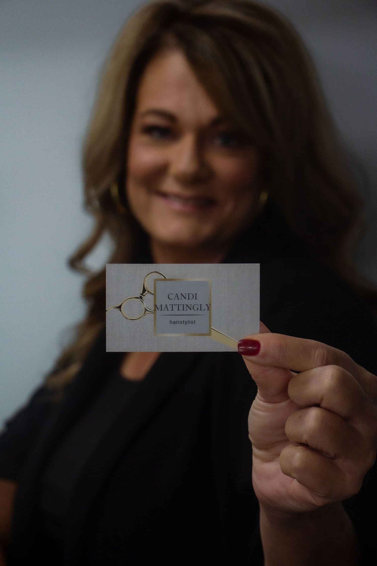 hair stylist posing for branding pictures holding business card.