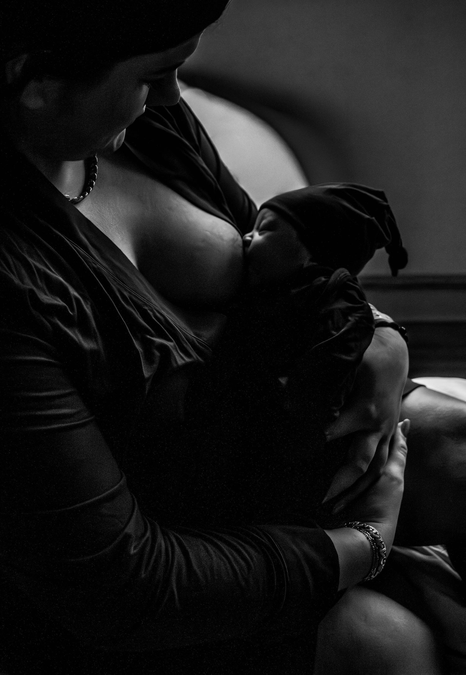 Black-and-white mother holding her newborn baby during a hospital session.