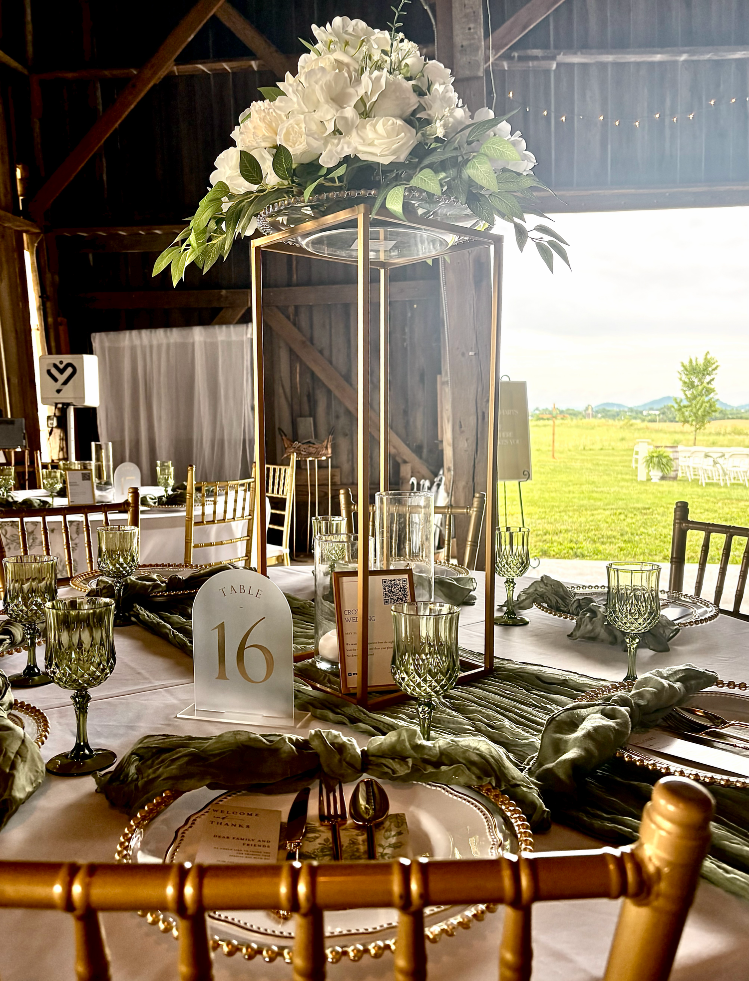 Gold tabletop display stand with white florals used as wedding reception table decor.
