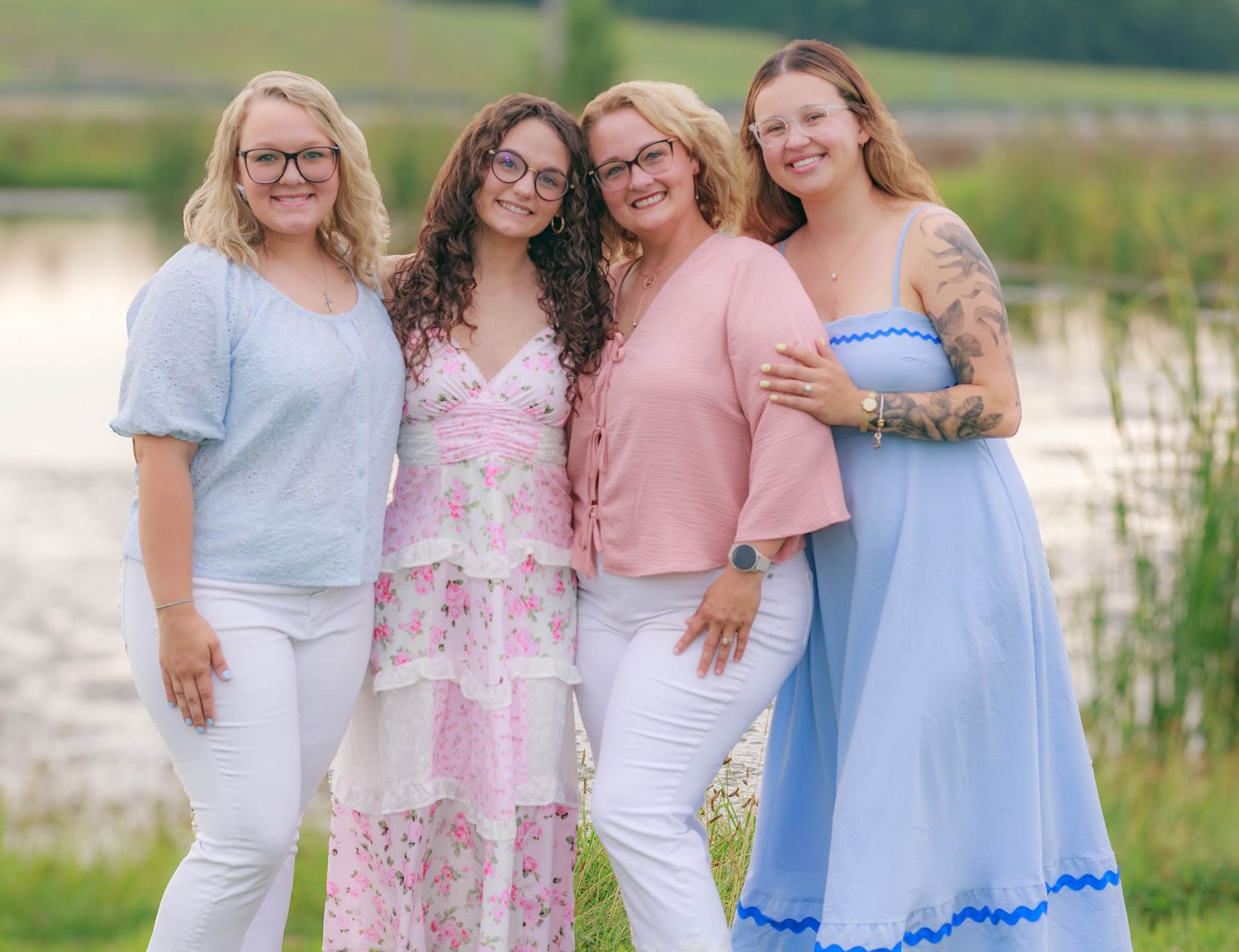 Four women posing together beside a pond during a family photography session